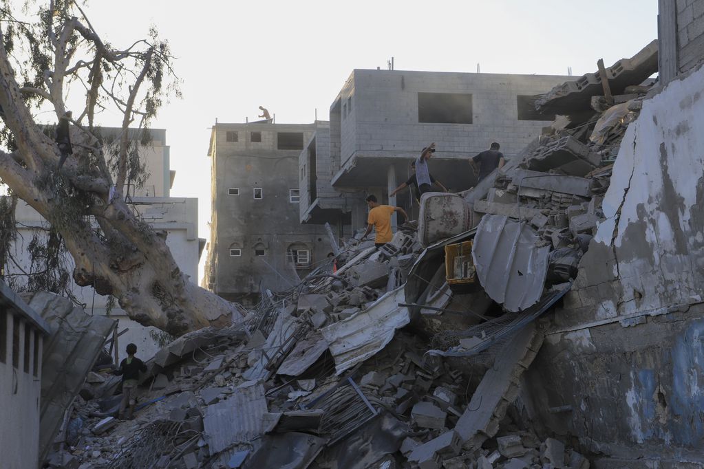 Palestinos buscan cuerpos y sobrevivientes entre los escombros de un edificio residencial destruido en un ataque aéreo israelí en Jan Yunis, Franja de Gaza, el miércoles 3 de julio de 2024. (AP Foto/Jehad Alshrafi)