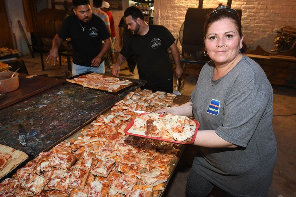 Gabriela Carmona, dueña del comedor, ayuda a preparar y cortar porciones de pizzas para repartir. | Foto: Los Andes