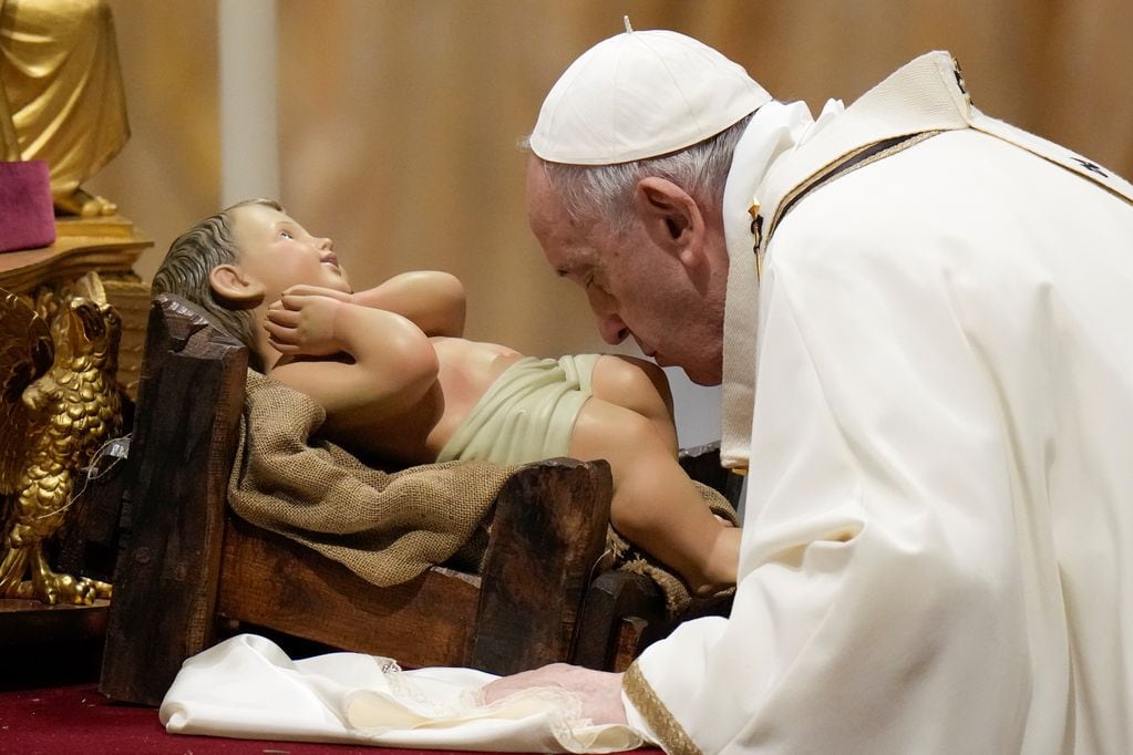 El Papa Francisco besa una estatua del Niño Jesús mientras celebra la Misa de Nochebuena.
