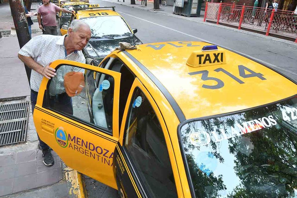 Carlos Encina limpia su taxi en una parada céntrica mientras espera el traslado de pasajeros. | Foto. José Gutiérrez / Los Andes