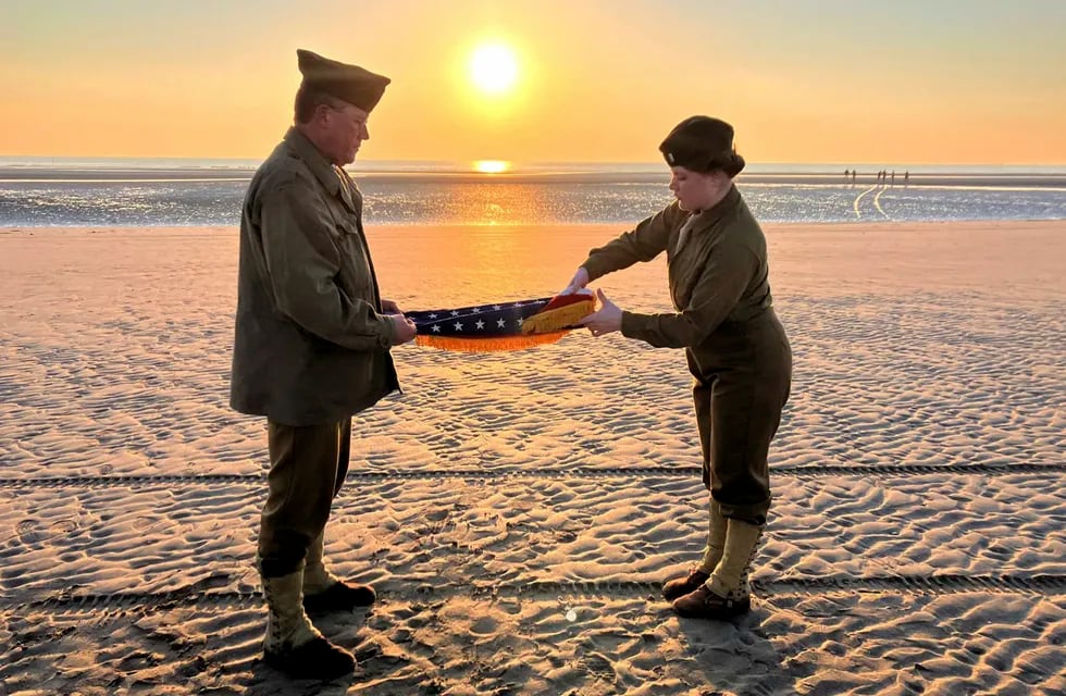 Christophe Receveur y su hija Julie, de Francia, extienden una bandera estadounidense que él compró hace seis meses en Gettysburg, Pensilvania, para conmemorar el Día D, el jueves 6 de junio de 2024 en la playa Utah, Normandía. (AP Foto/John Leicester)