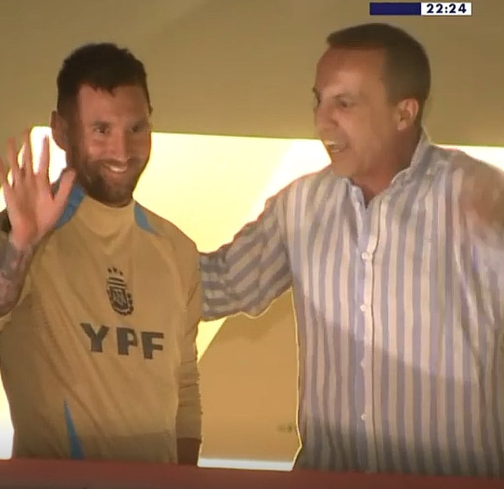 Lionel Messi saludando a los hinchas de la selección desde la ventana del hotel junto a un personaje televisivo de España. (Imagen de TV)