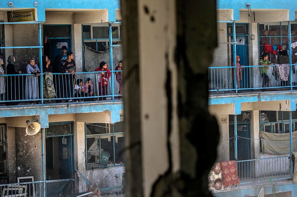 Palestinos refugiados en una escuela de la UNRWA en el centro el centro de Gaza miran desde los balcones los daños causados por un un ataque aéreo israelí, este 6 de junio. EFE/EPA/Mohammed Saber