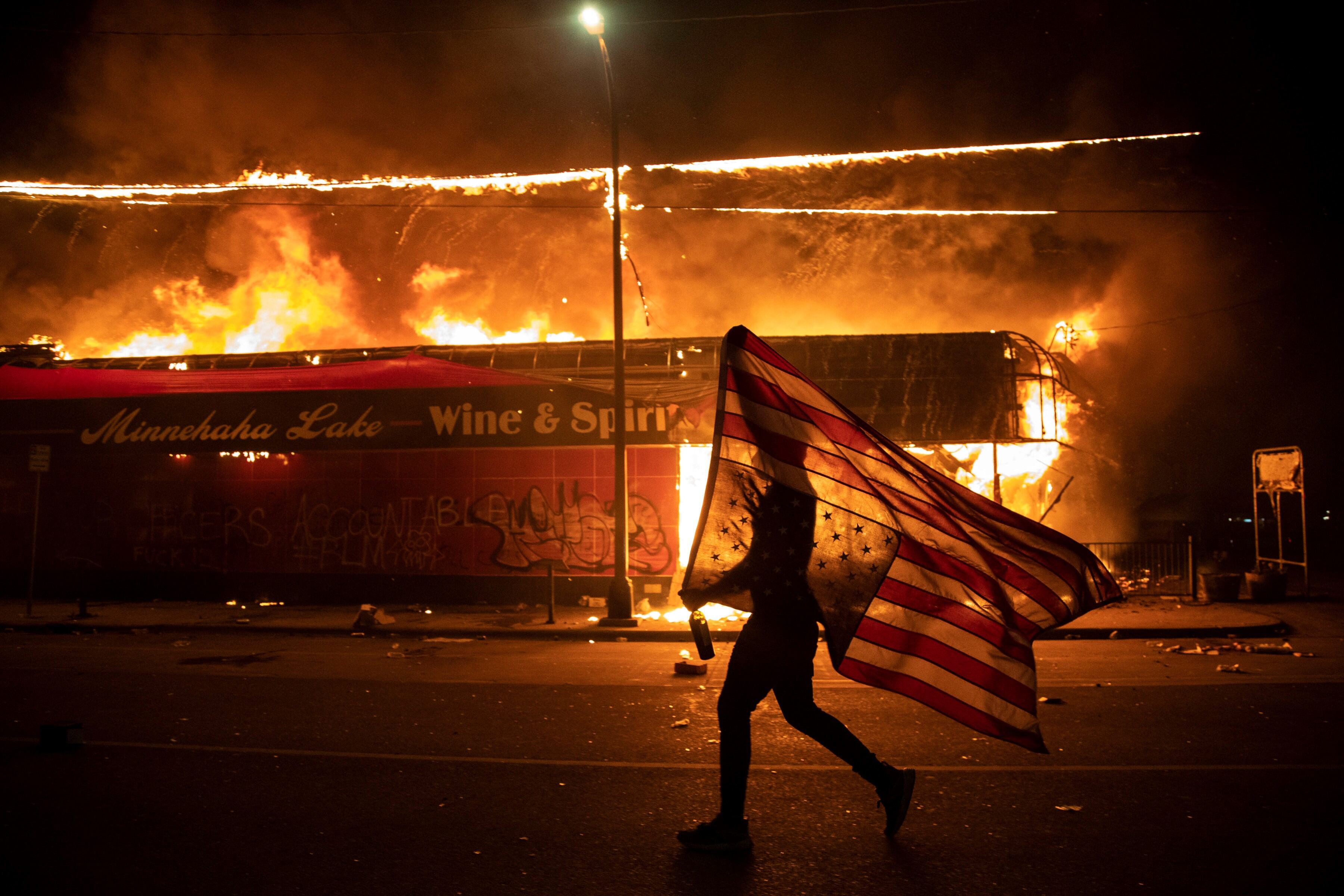 Julio Cortez la noche del 28 de mayo en Minneapolis, muestra a un manifestante solitario que corre con una bandera estadounidense invertida