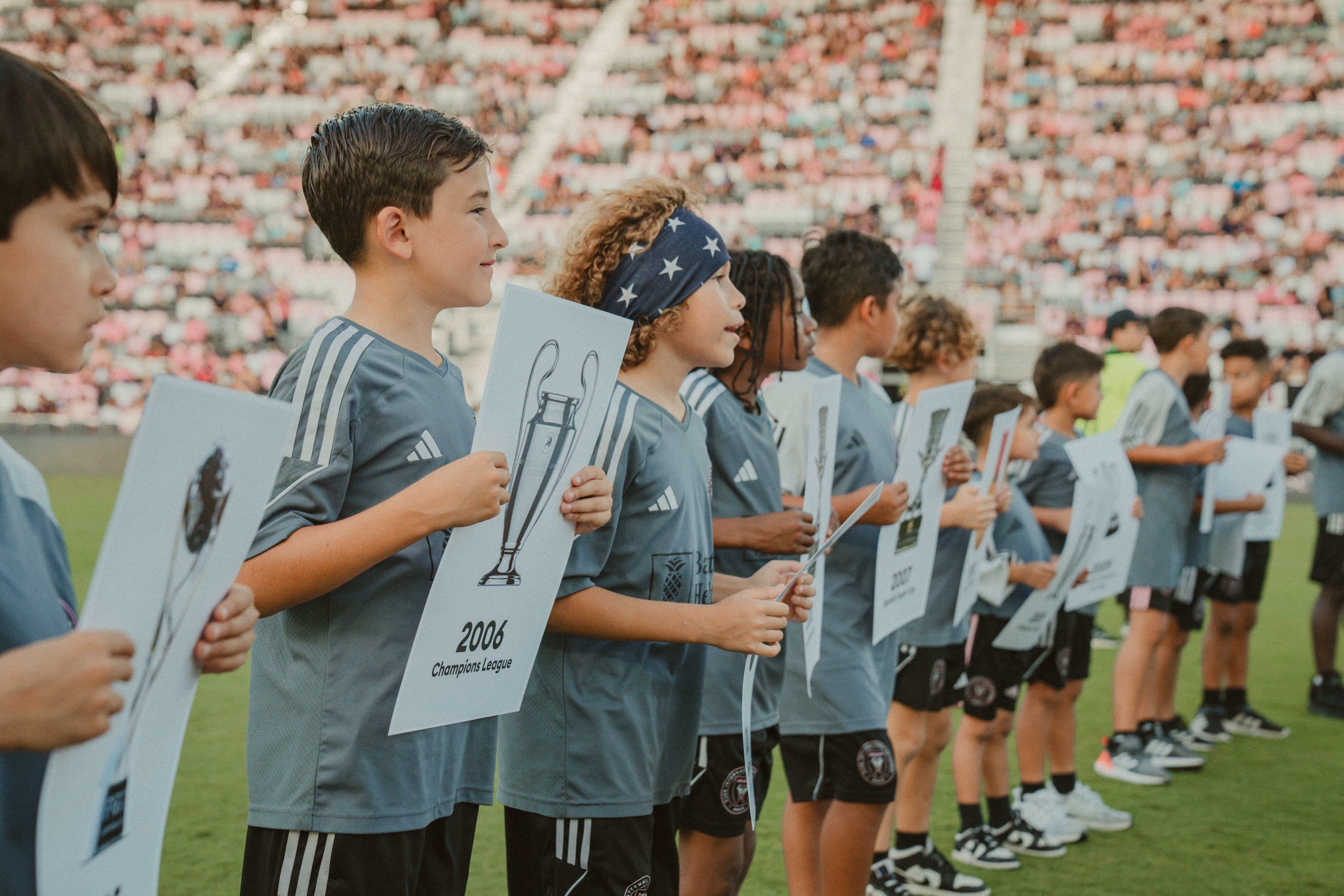 Jugadores de las infantiles del Inter Miami sostienes imágenes de todos los títulos de Messi. Foto: Inter Miami.