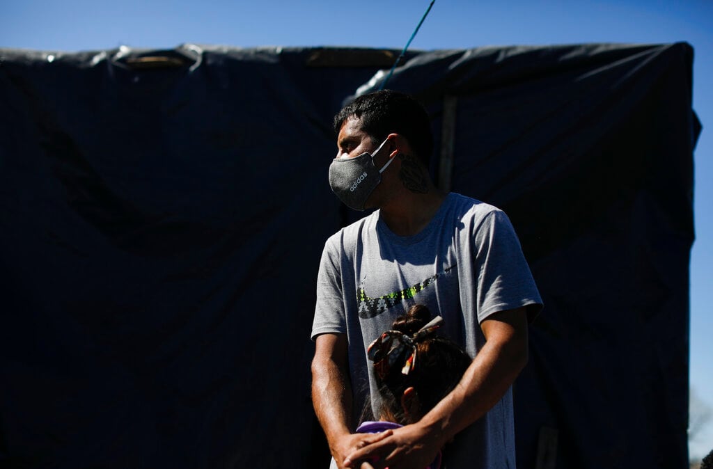 Un hombre abraza a su hija frente a su casa improvisada en un campamento de ocupantes ilegales en Guernica, provincia de Buenos Aires,