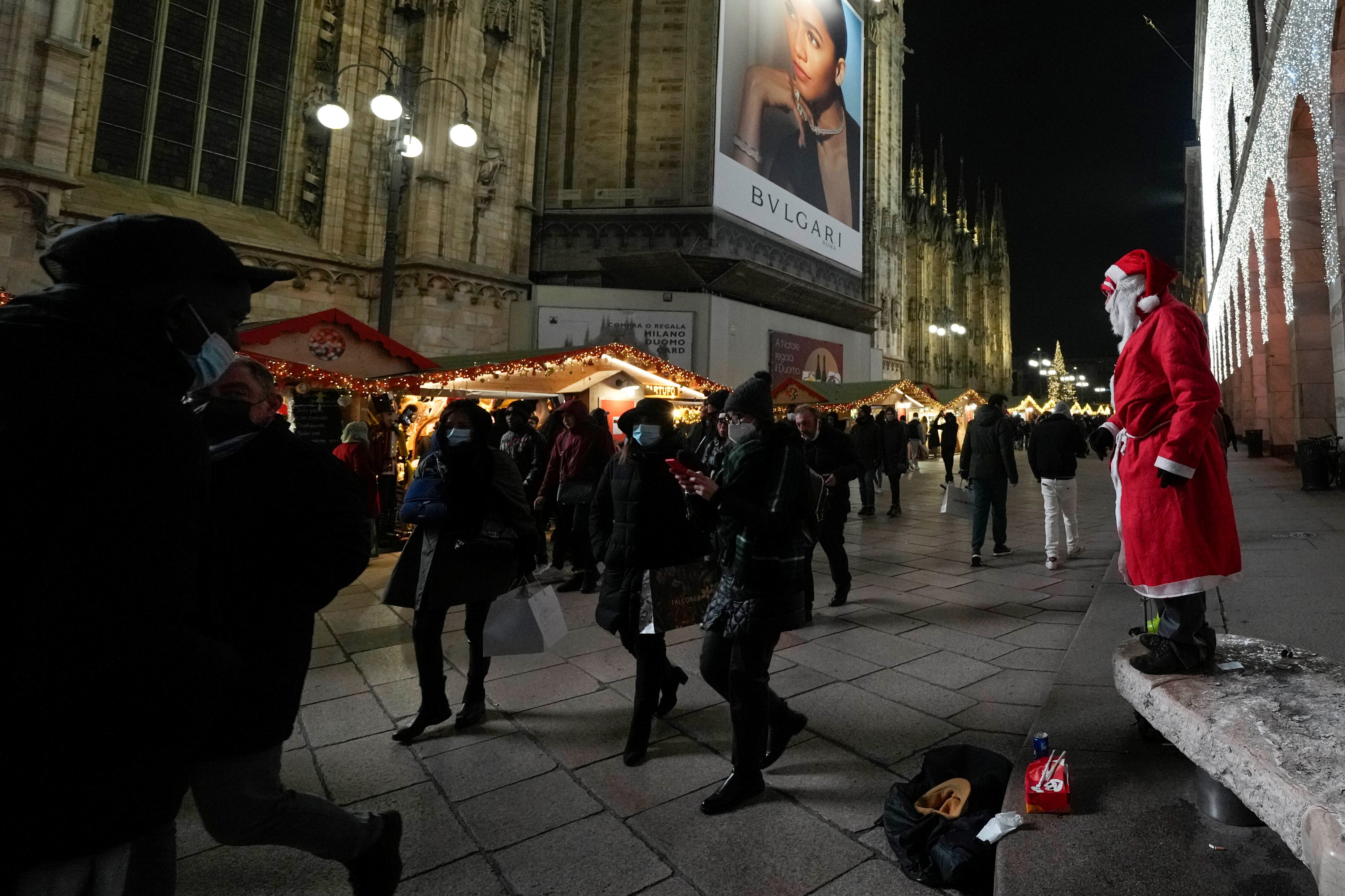 Los peatones pasan frente a la catedral gótica del Duomo con barbijos en Milán, Italia.