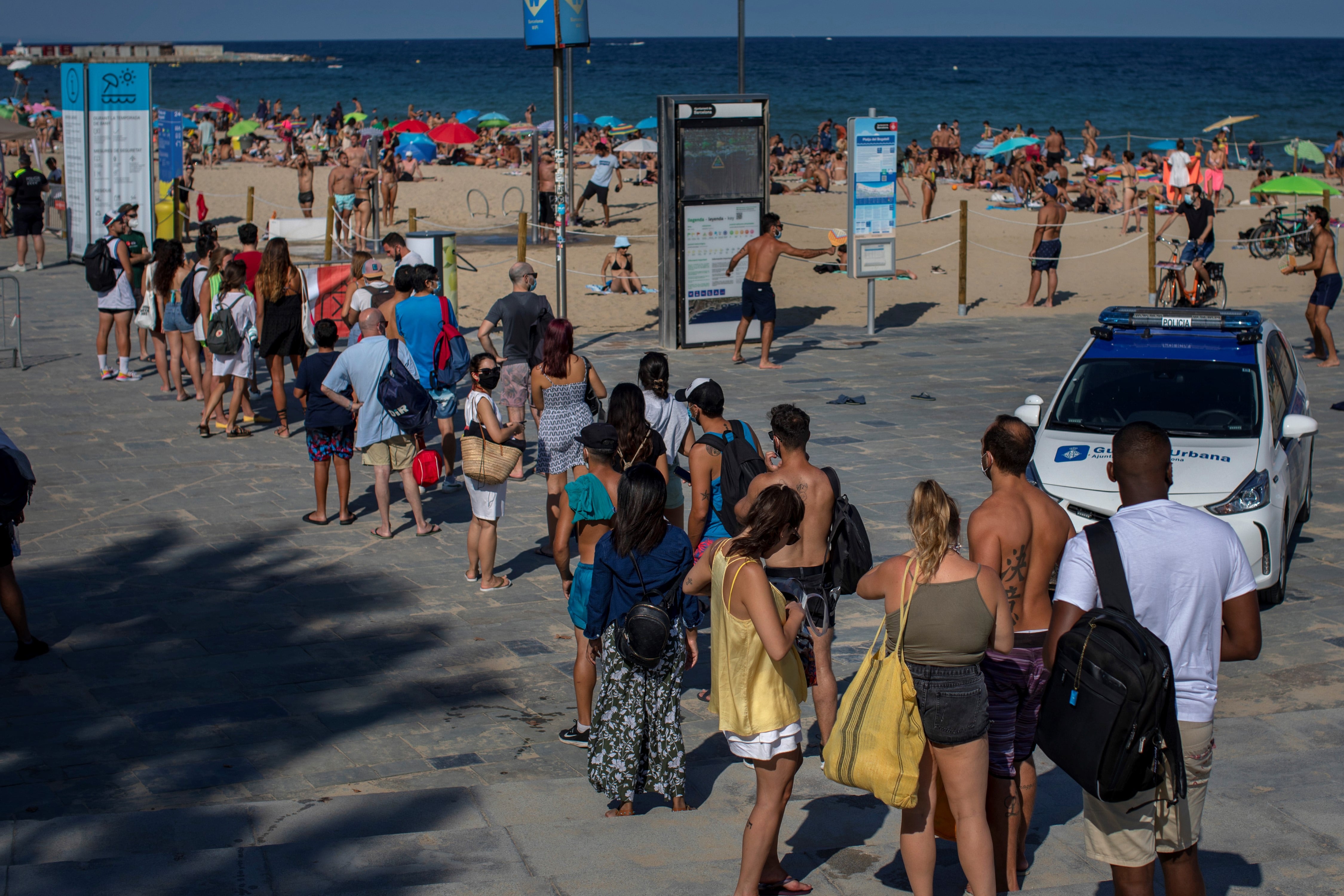 La gente espera para ingresar a una playa que fue cerrada por la policía debido al hacinamiento en Barcelona.