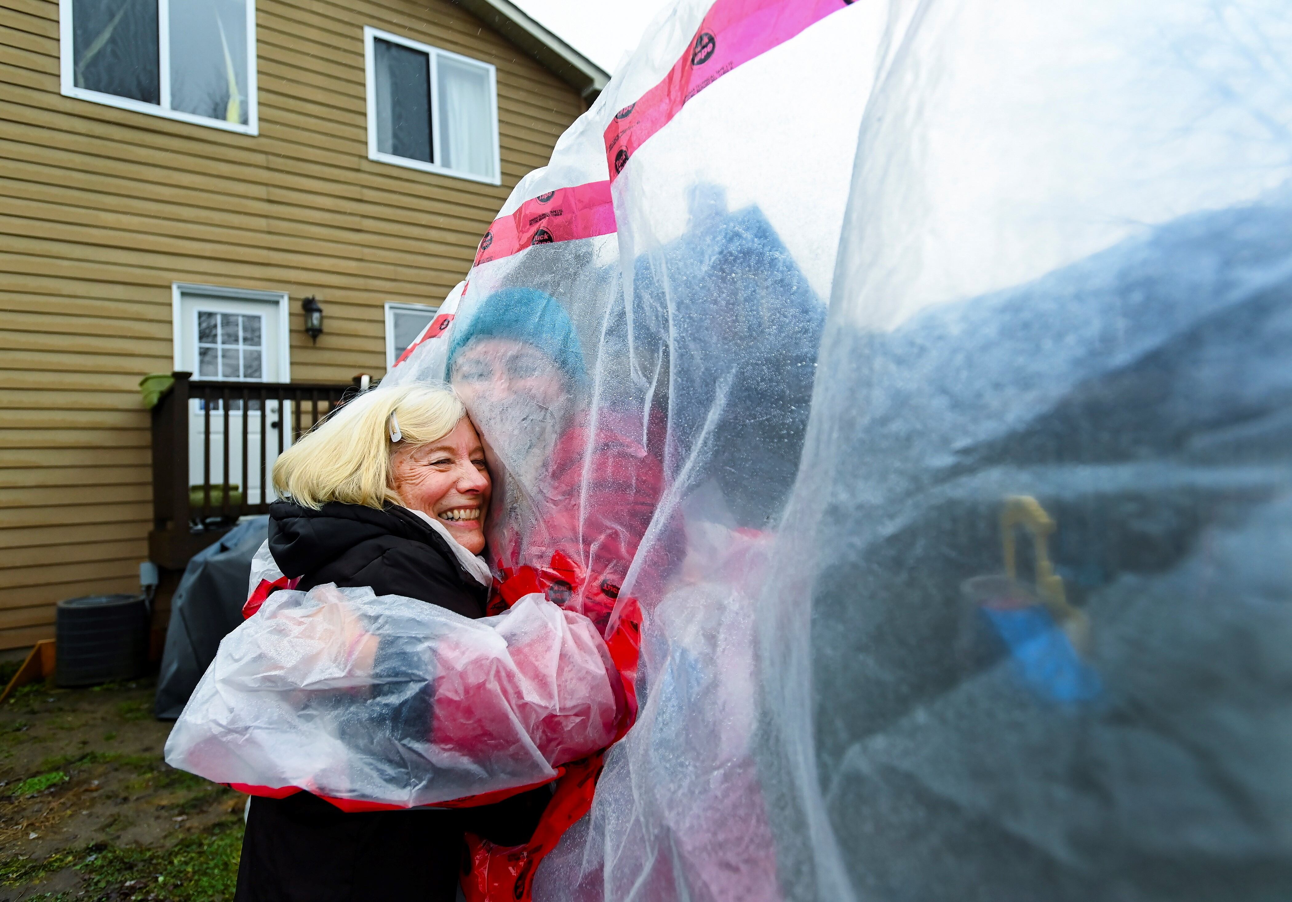 Carolyn Ellis, izquierda, creadora del guante de abrazo abraza a su madre Susan Watts, de 74 años, en su patio trasero en Nochebuena durante la pandemia de COVID-19 en Guelph, Ontario.