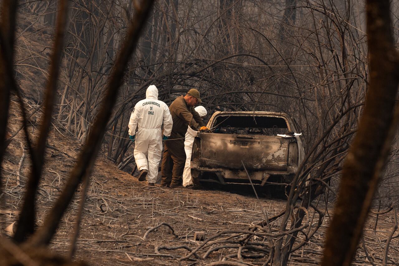 Efectivos policiales investigan un auto afectado por los incendios ayer, cerca a la ciudad de Santa Juana (Chile). Foto: EFE