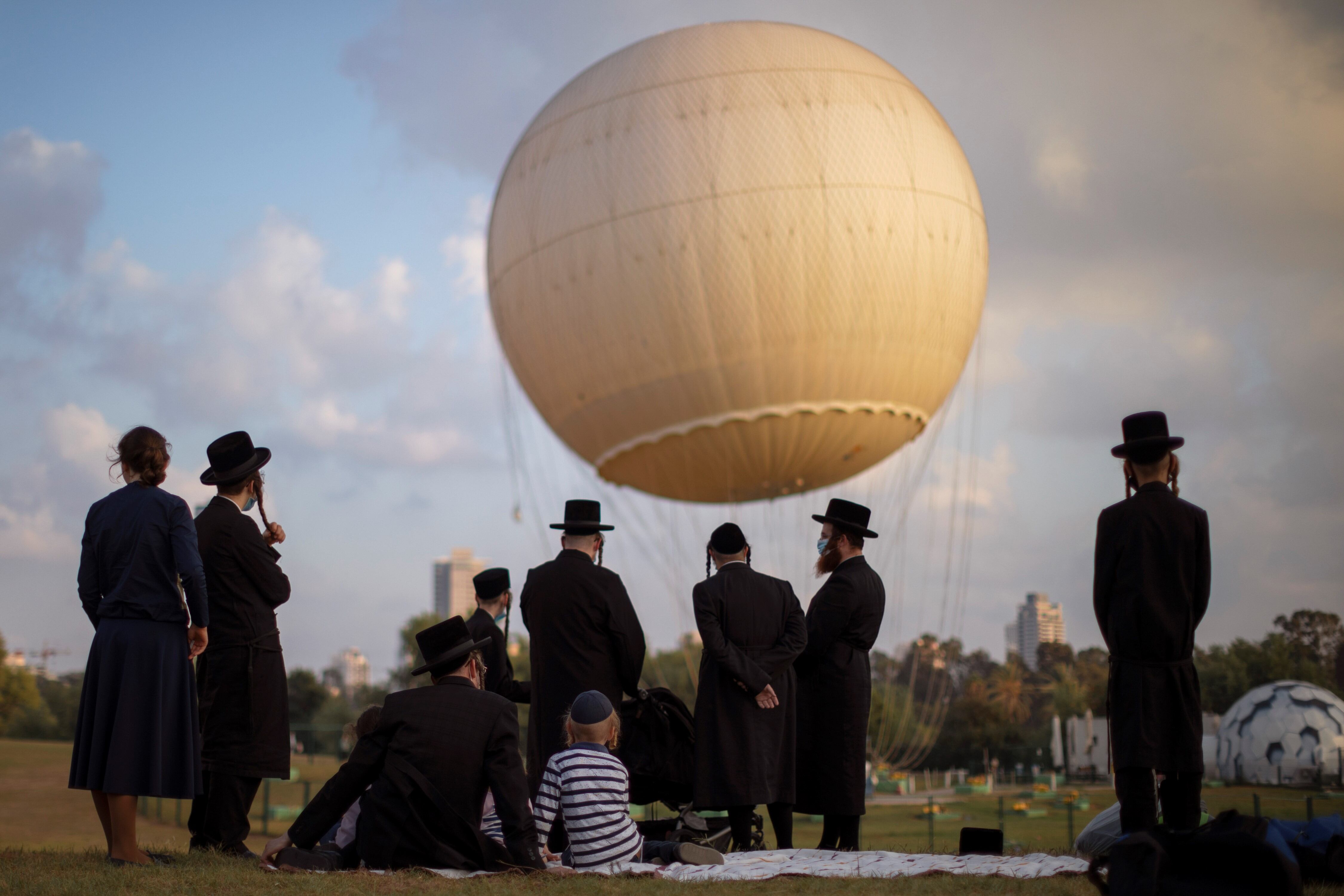 Judíos ultraortodoxos, algunos con mascarilla protectora en medio de preocupaciones por el brote de coronavirus en el país, pasan el día en un parque en Tel Aviv. AP