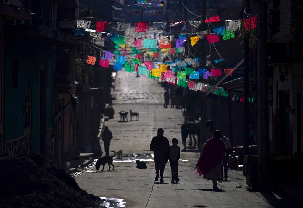 Peatones pasan por debajo de las banderolas de colores que quedan de las celebraciones navideñas en la comunidad indígena de Puerpecha, México