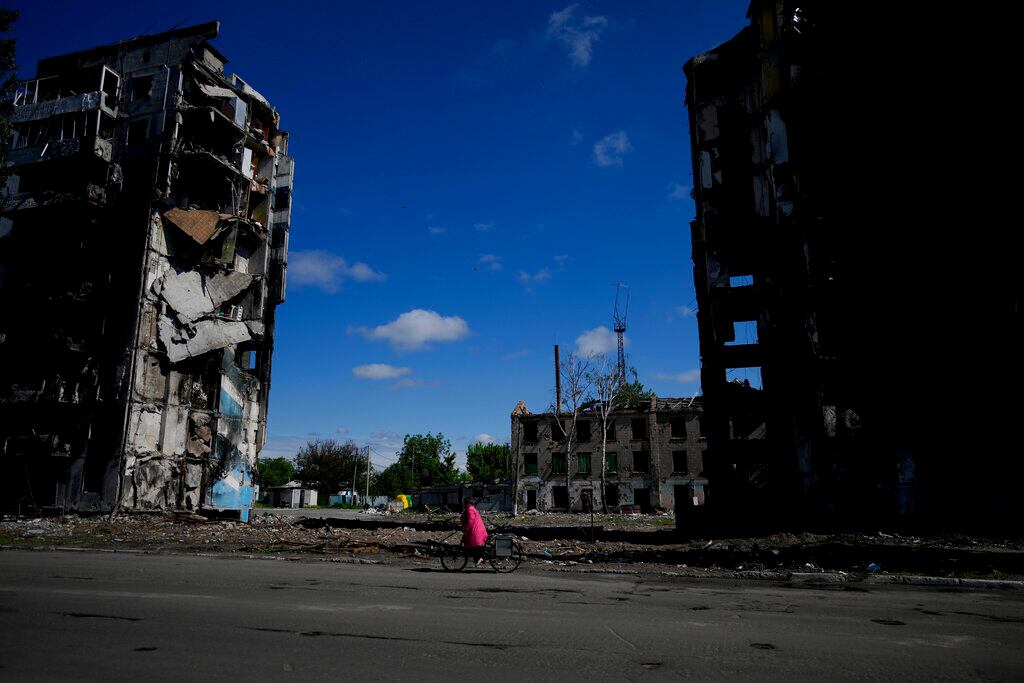 Una mujer monta en bicicleta cerca de edificios destruidos por ataques en Borodyanka, a las afueras de Kiev, Ucrania. Foto AP