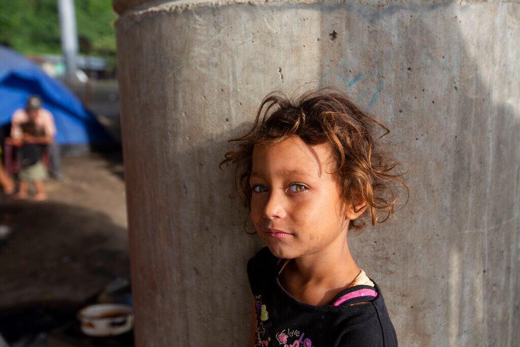 Katerine espera a que su familia prepare el desayuno debajo de un puente a las afueras de San Pedro Sula, Honduras,