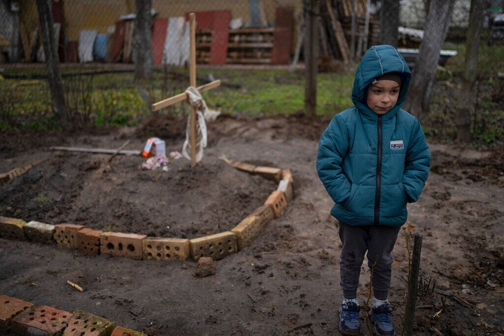 En esta imagen de archivo, en el patio de su casa, Vlad, de 6 años, de pie junto a la tumba de su madre, a en Bucha, a las afueras de Kiev, Ucrania, el 4 de abril de 2022. La madre de Vlad murió el mes pasado luego de que la familia se vio obligada a refugiarse en un sótano durante la ocupación del ejército ruso. Por el momento se desconocen las causas de su muerte. (AP Foto/Rodrigo Abd)