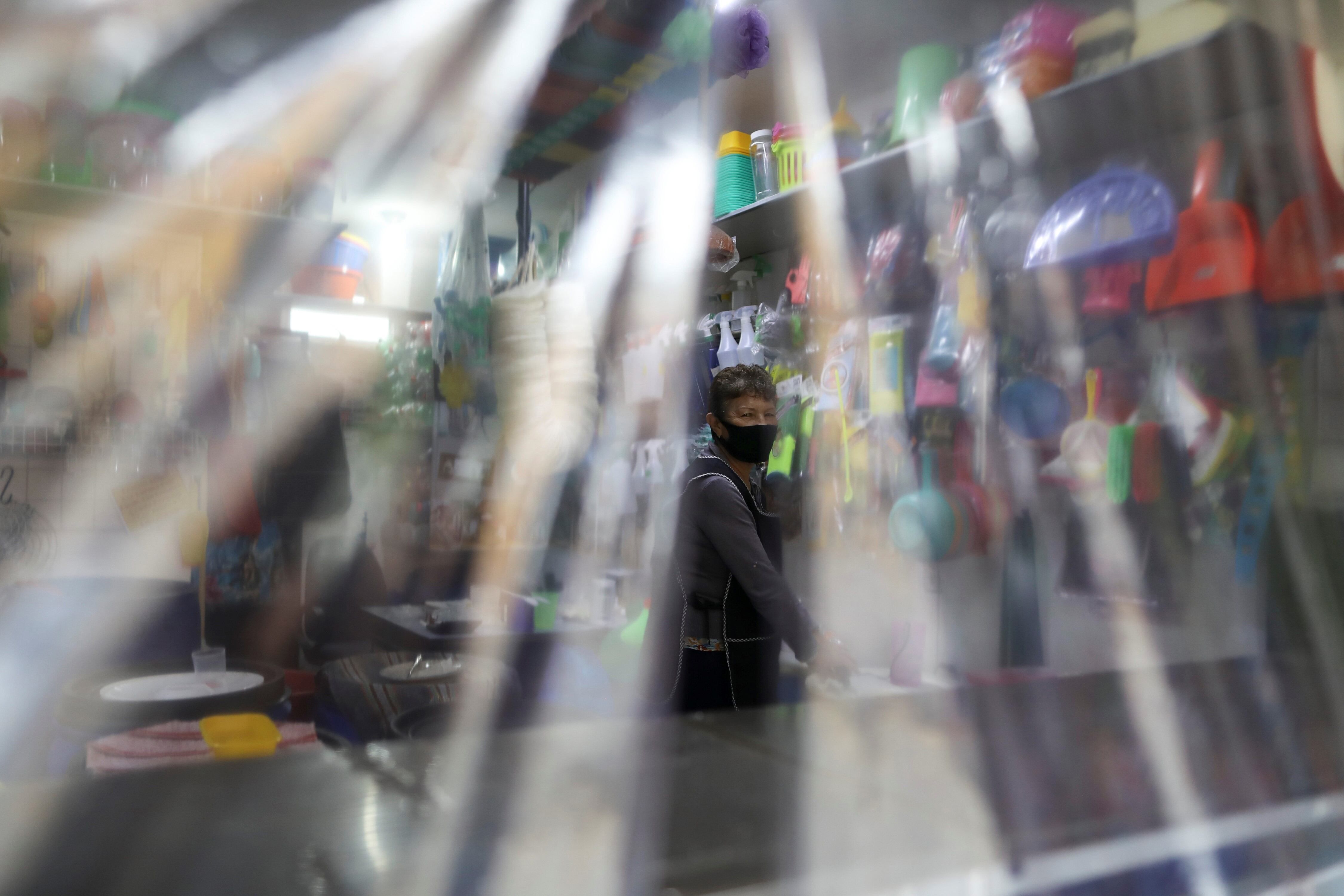 Un comerciante se encuentra detrás del mostrador, protegido con láminas de plástico en un comercio de México.