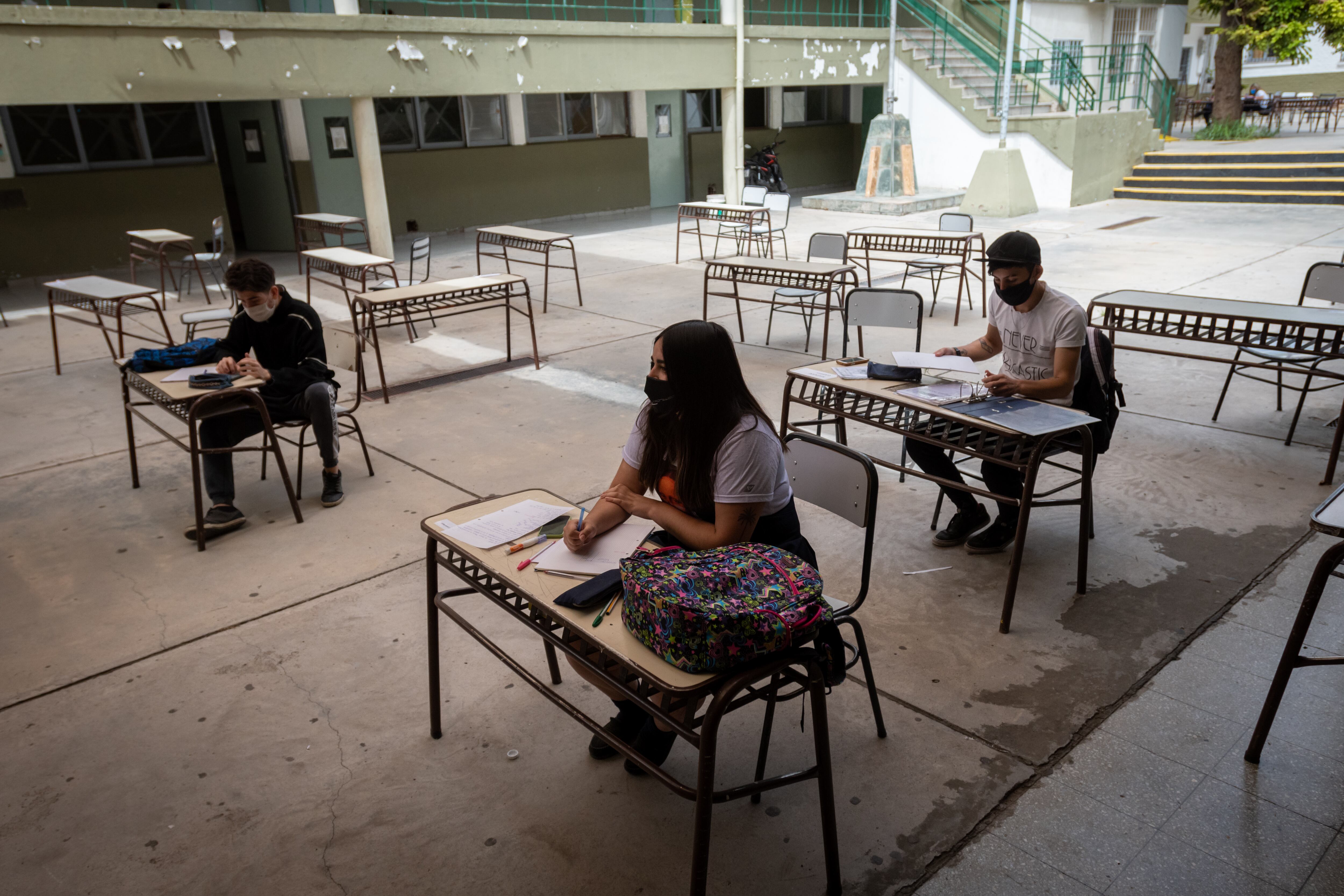 Algunos chicos toman sus clases en el patio de la escuela Manuel Belgrano de Godoy Cruz.