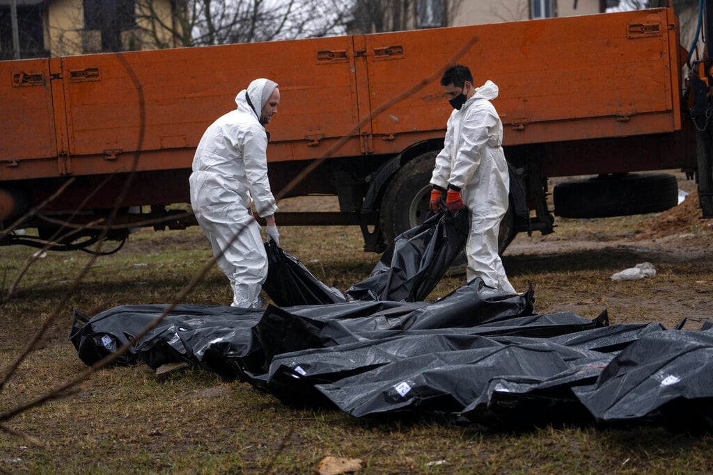 Trabajadores de un cementerio llevan un cadáver de una fosa común a una morgue para ser identificado, el domingo 10 de abril de 2022, en Bucha, a las afueras de Kiev, Ucrania. (AP Foto/Rodrigo Abd)