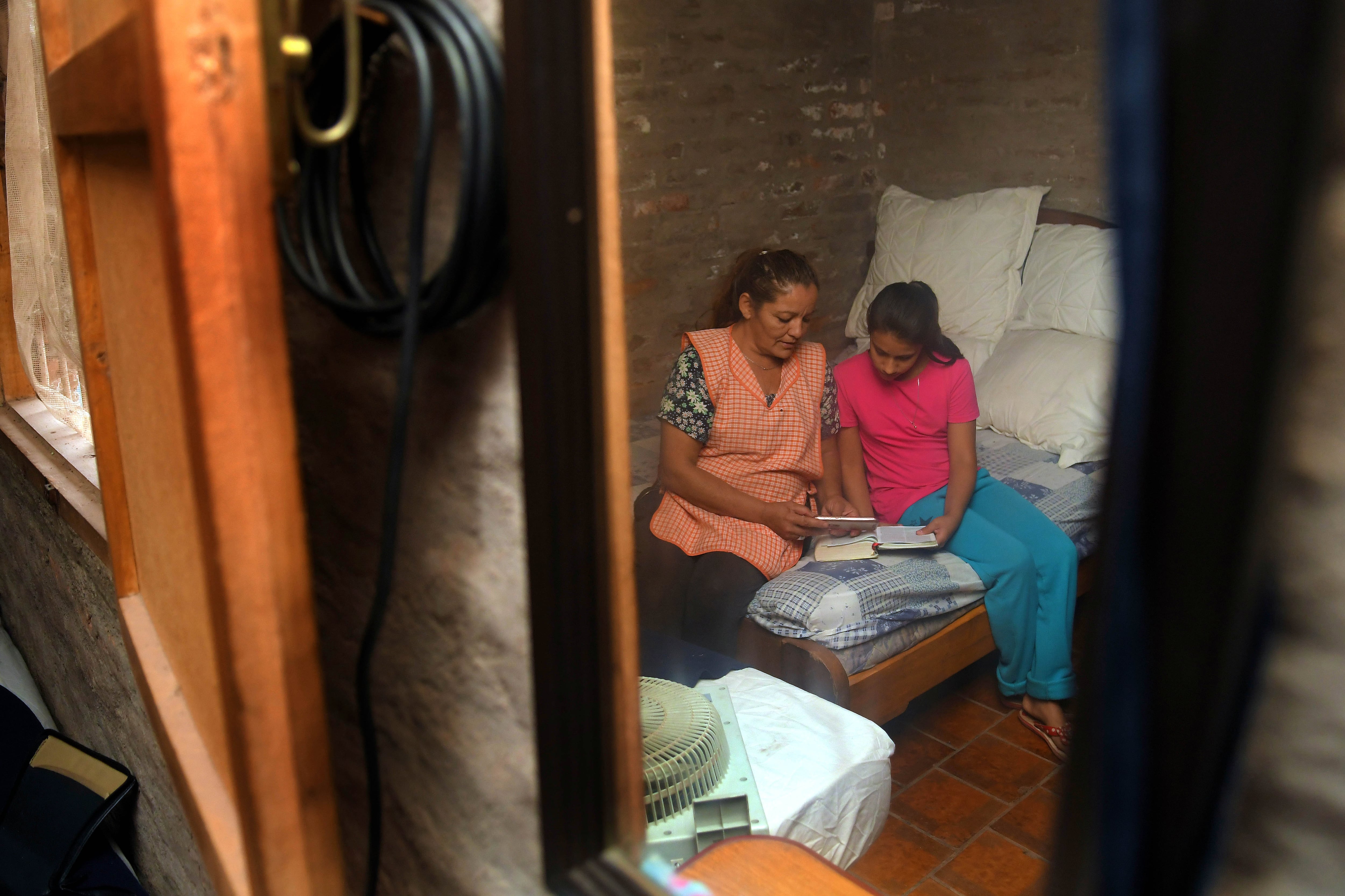 Abril. Rebeca Acuña (9) y su tía Graciela Soria  hacen los deberes de la escuela, por internet, a través de un celular.