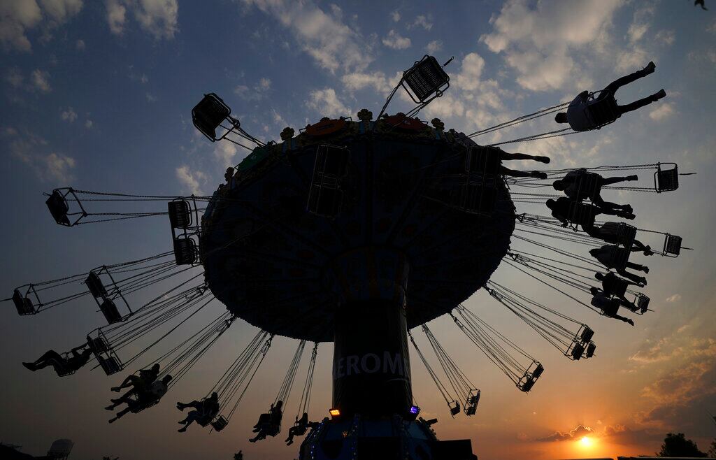 Mexicanos, a bordo de una atracción de feria durante el festival de música Ceremonia, en la Ciudad de México, el 2 de abril de 2022. (AP Foto/Fernando Llano)