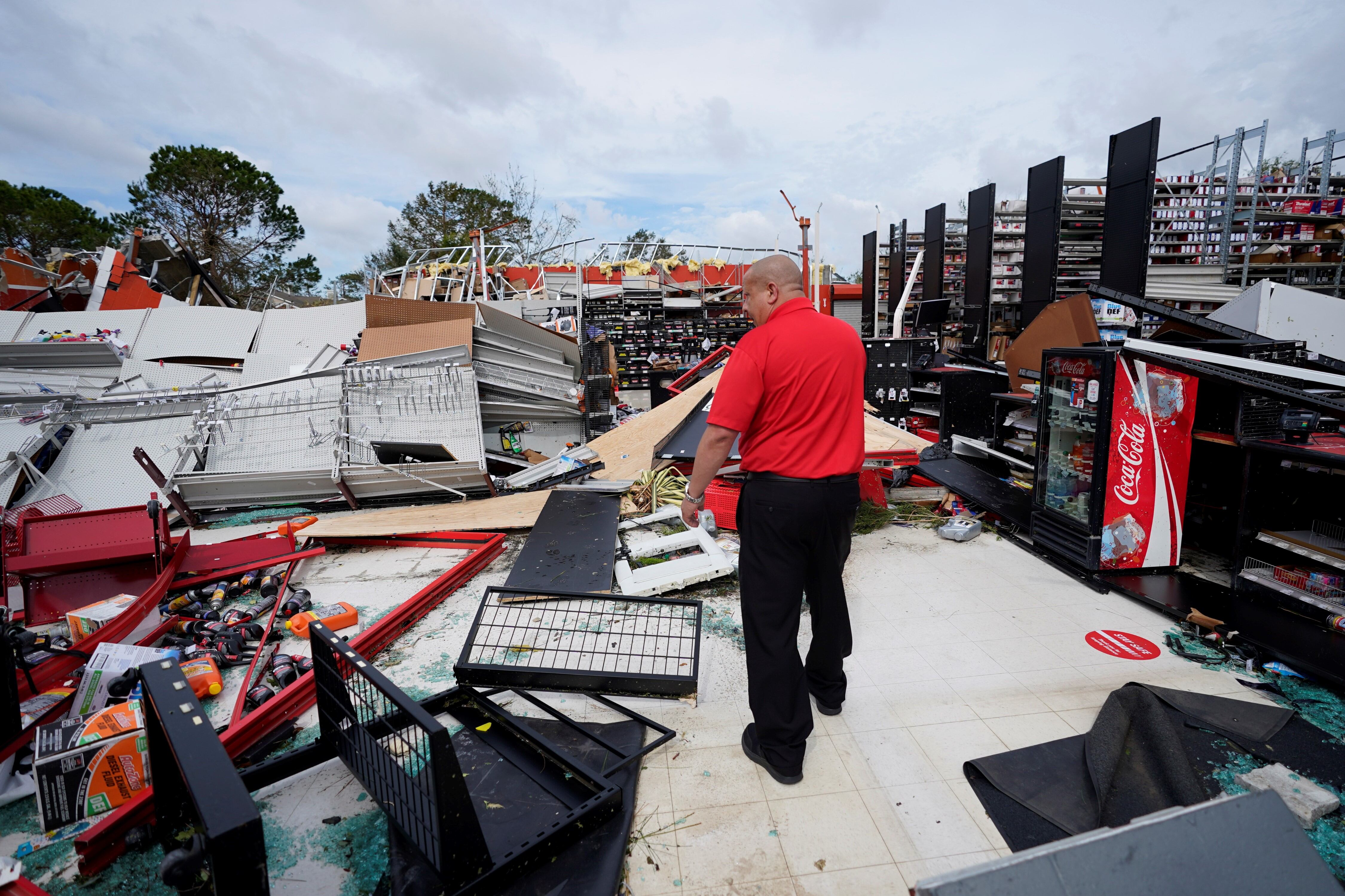 Un empleado de una tienda de autopartes inspecciona los daños a las instalaciones.