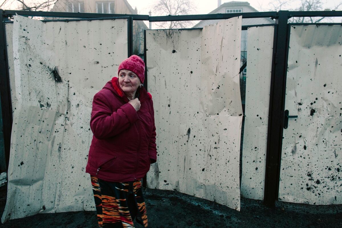 Una mujer pasa junto a una valla dañada de un edificio residencial después de que un cohete impactara en el barrio de Pisochyn, en las afueras de Kharkiv. EFE