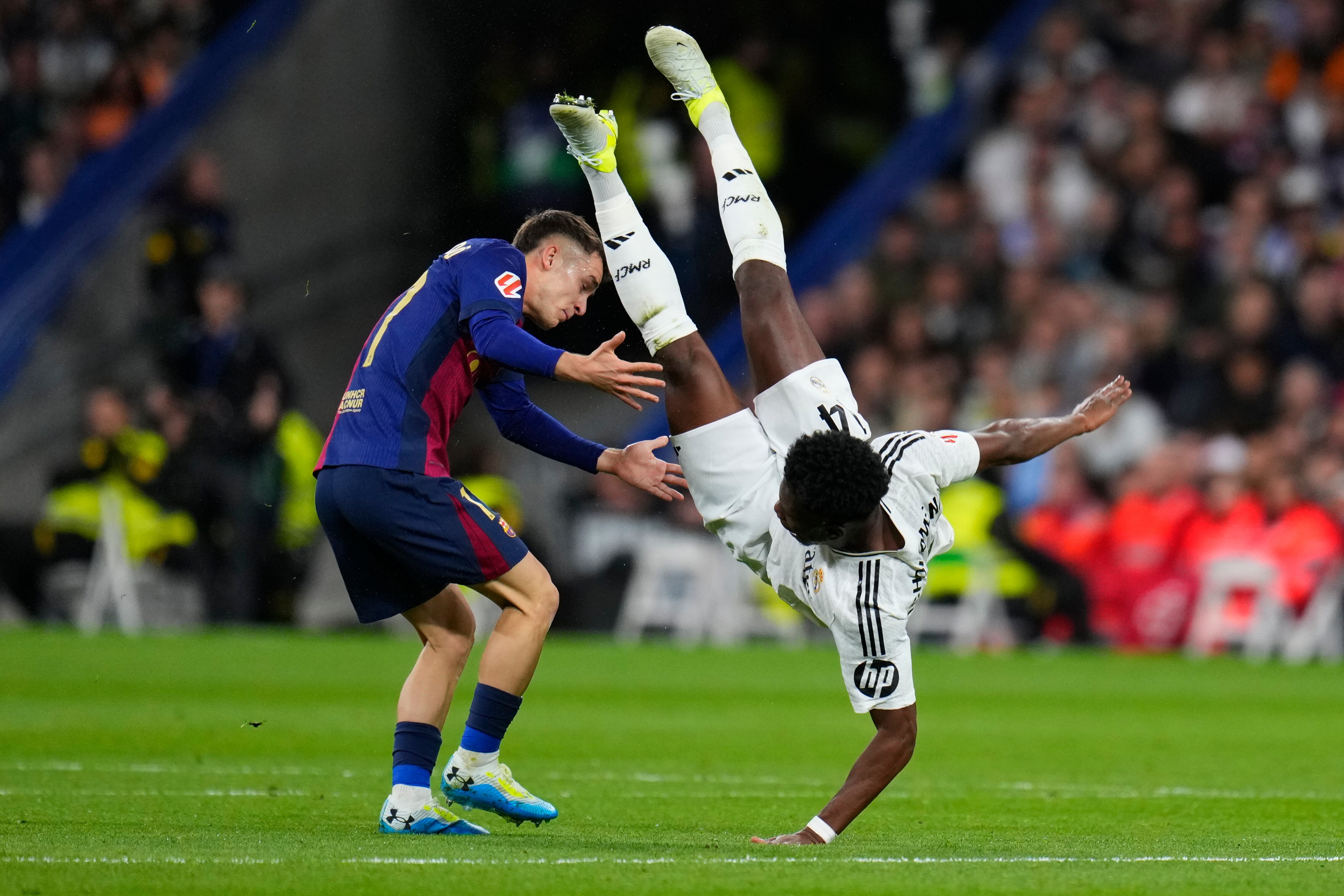 Aurelien Tchouameni (derecha) del Real Madrid cae al lado de Marc Casadó del Barcelona en el partido por la Liga española, el sábado 26 de octubre de 2024. (AP Foto/Manu Fernández)