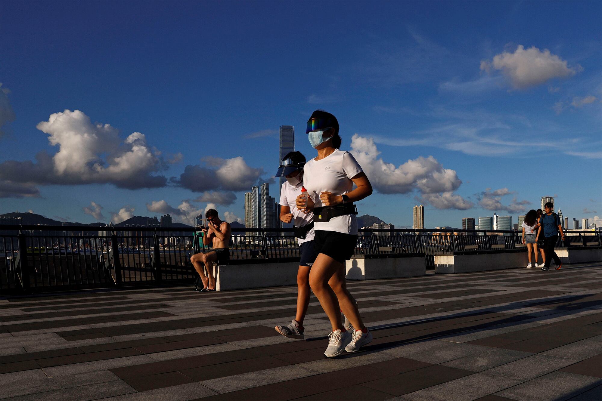 Personas que usan mascarillas para protegerse contra el nuevo coronavirus corren en un parque en Hong Kong.