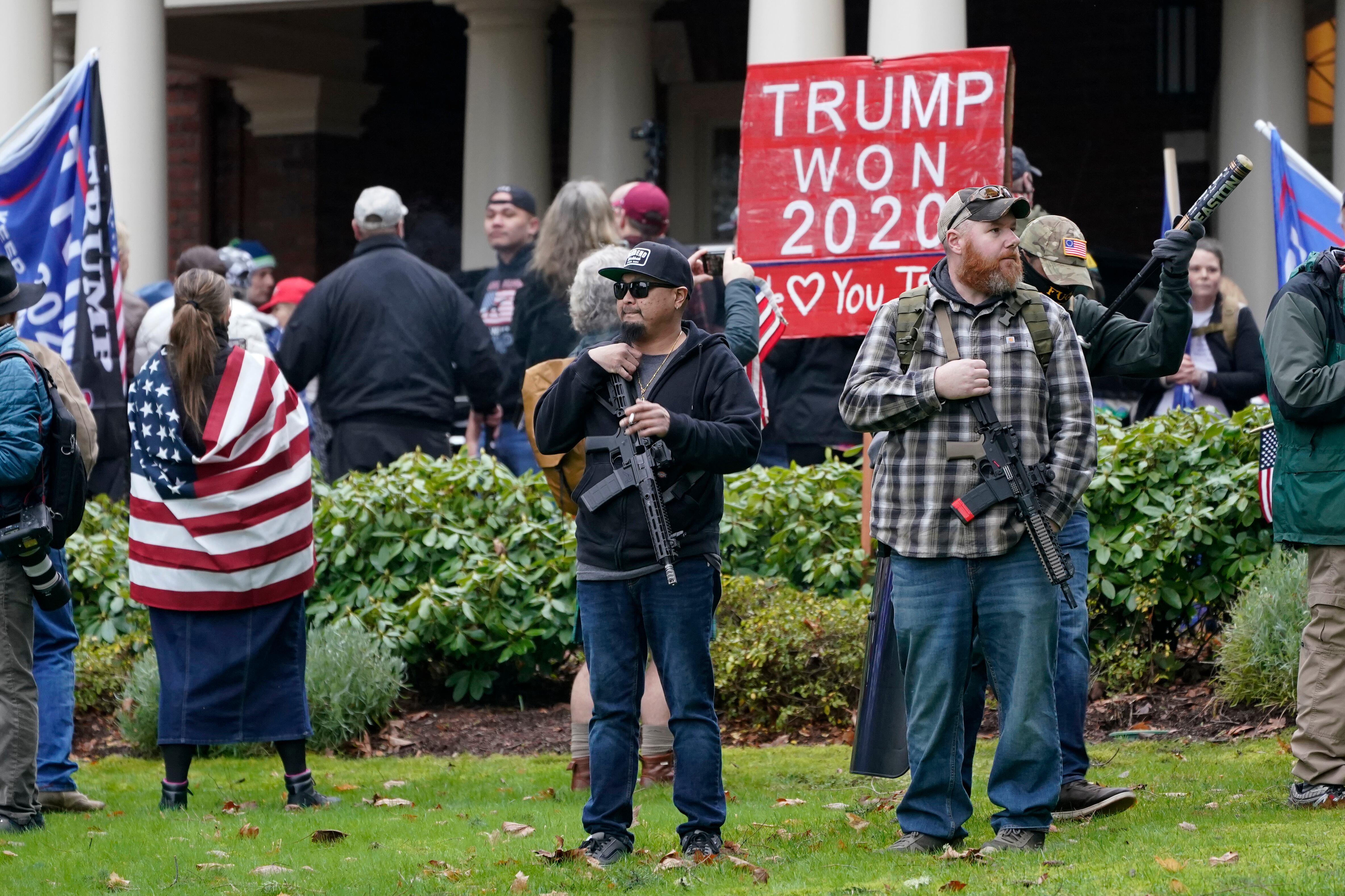 Partidarios de Trump, algunos portando armas de fuego, permanecen afuera de la mansión del gobernador después de irrumpir en la cerca perimetral en el Capitolio.