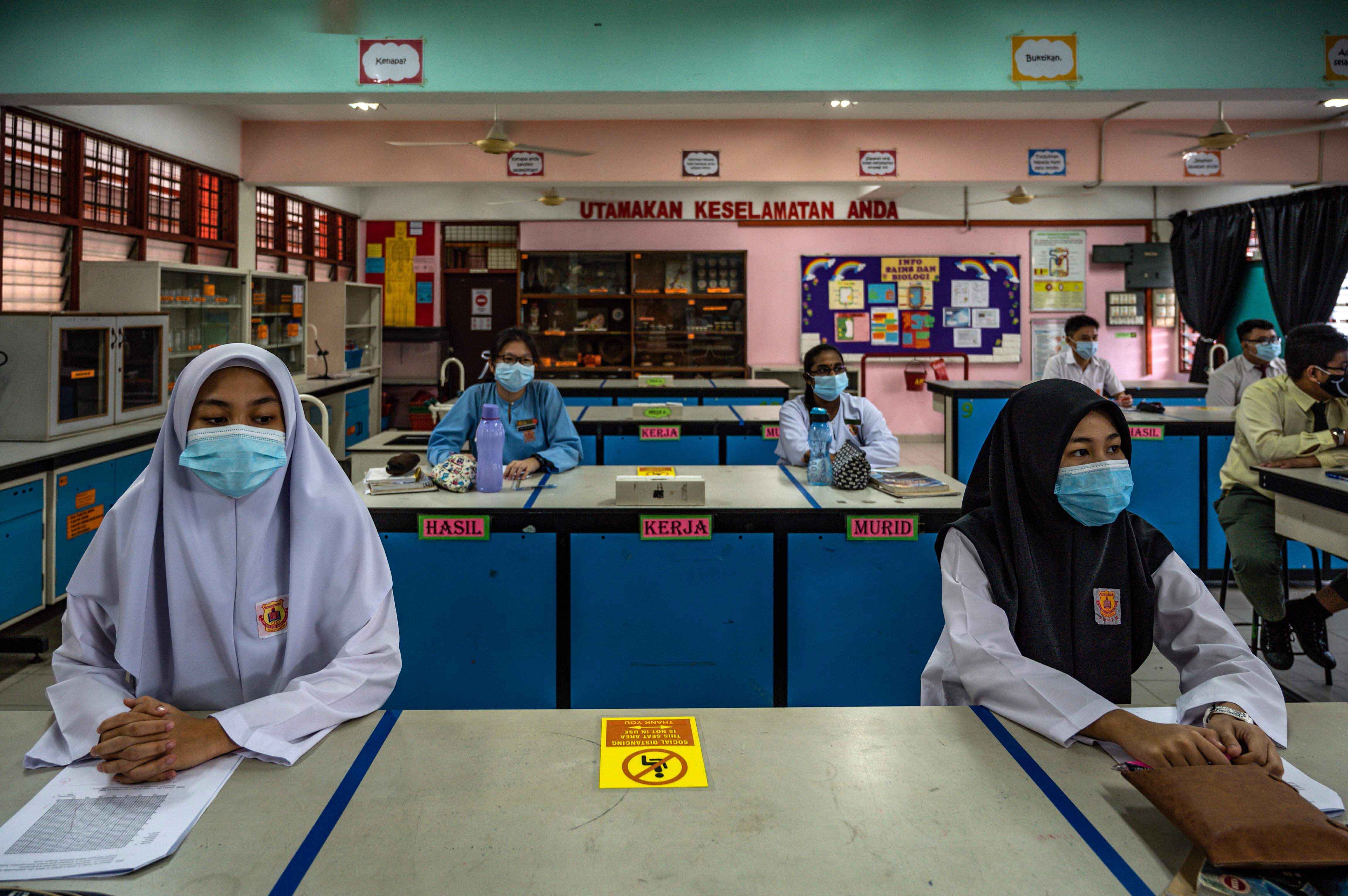 Los estudiantes de secundaria usan máscaras faciales en un salón de clases el primer día después de ser reabiertos, luego de las restricciones para detener la propagación del coronavirus COVID-19 en Kuala Lumpur el 24 de junio de 2020. / AFP / Mohd RASFAN