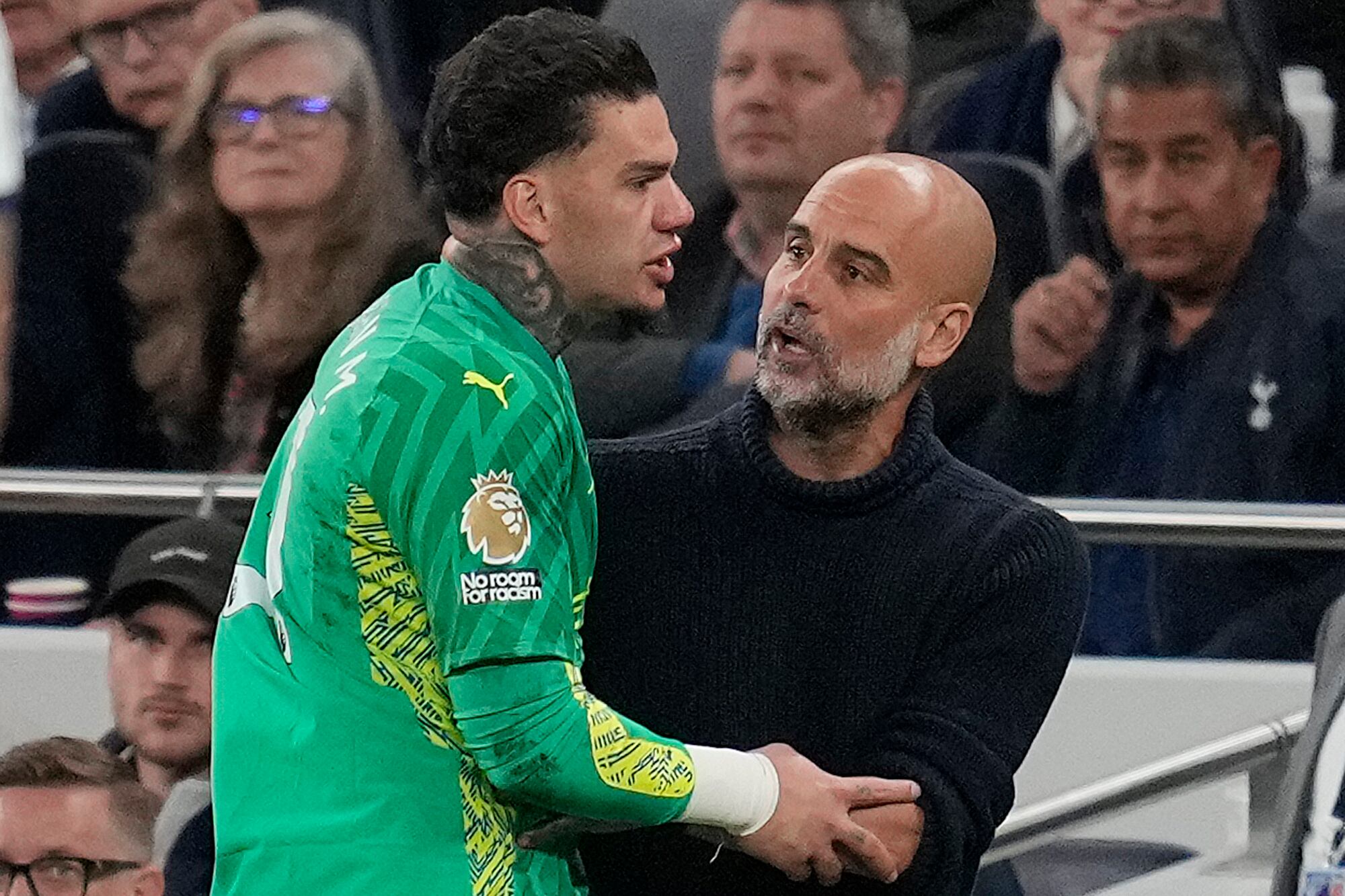 El arquero del Manchester City Ederson conversa con el técnico Pep Guardiola al salir del partido contra Tottenham en la Liga Premier, el martes 14 de mayo de 2024.(AP Foto/Kin Cheung)