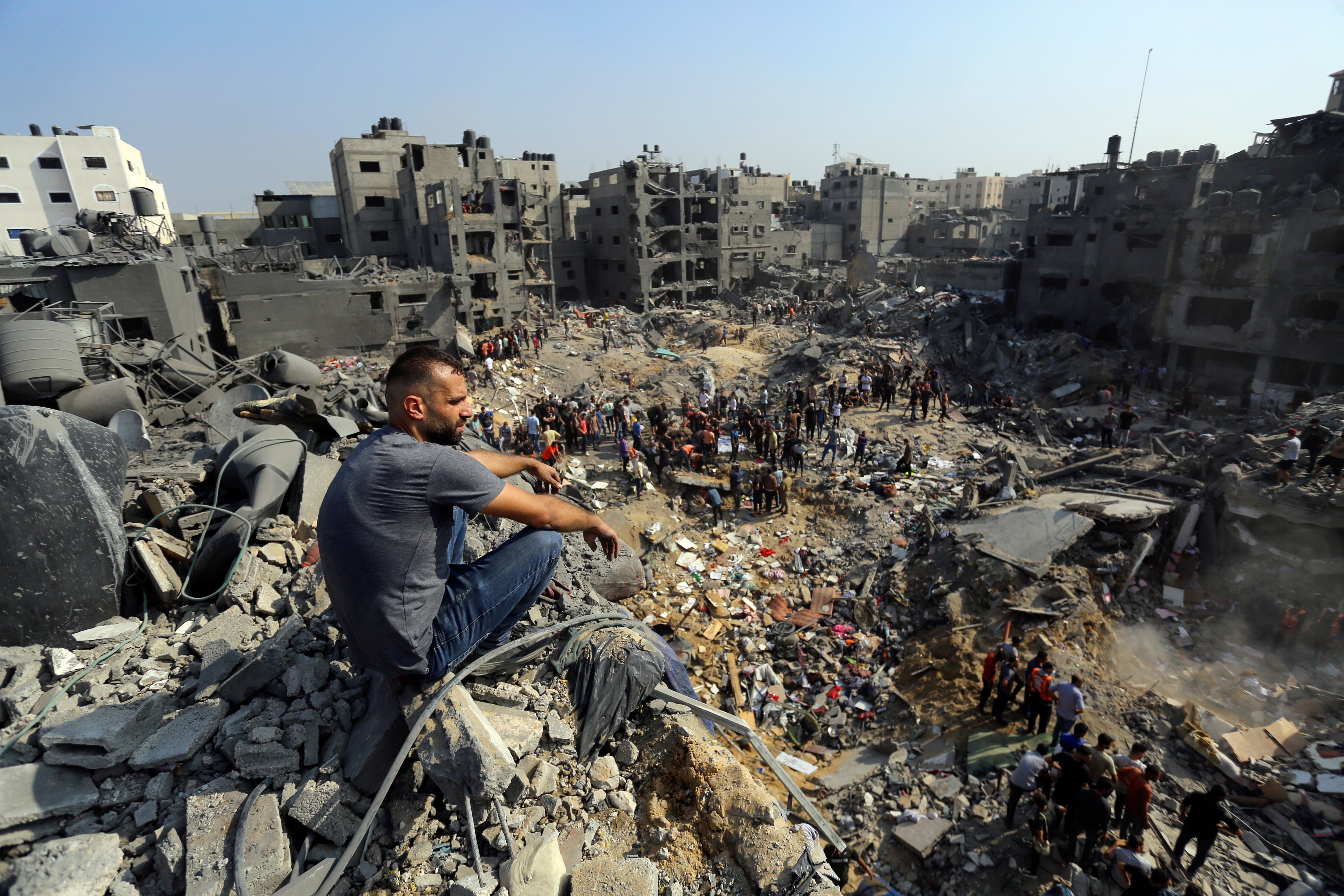 Un hombre se sienta sobre los escombros mientras otros buscan entre los restos de edificios atacados por la aviación israelí, en el campo de refugiados de Jabaliya, en el norte de la Franja de Gaza, el 1 de noviembre de 2023. (AP Foto/Abed Khaled)