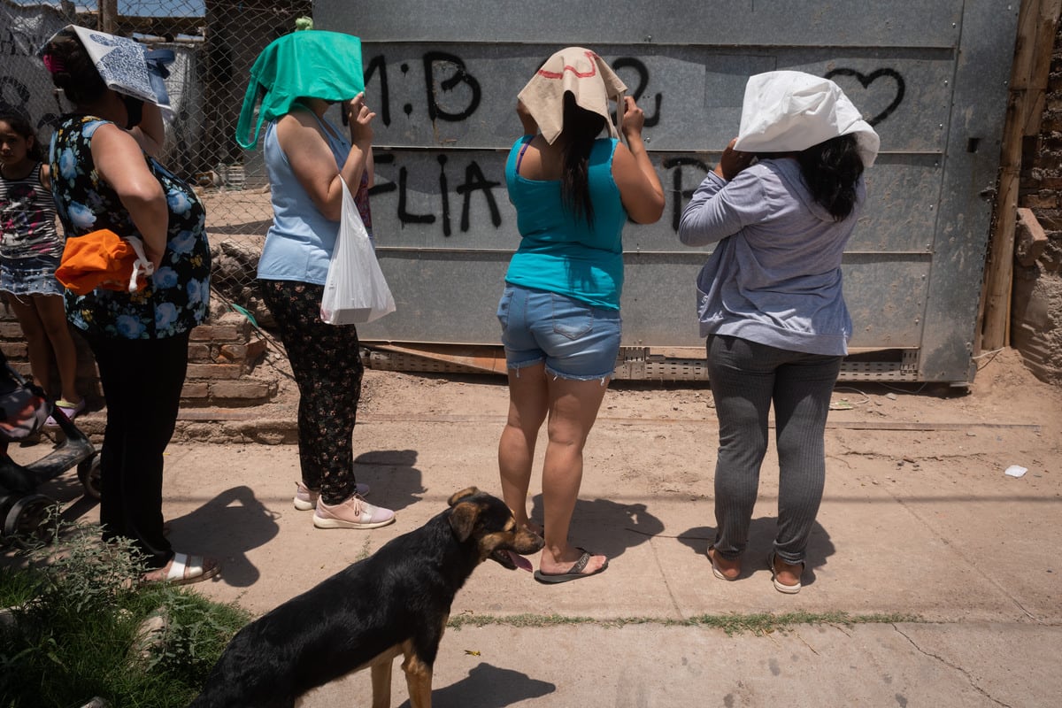 Los familias del asentamiento esperan bajo un intenso calor que les entreguen el bolsón con alimentos