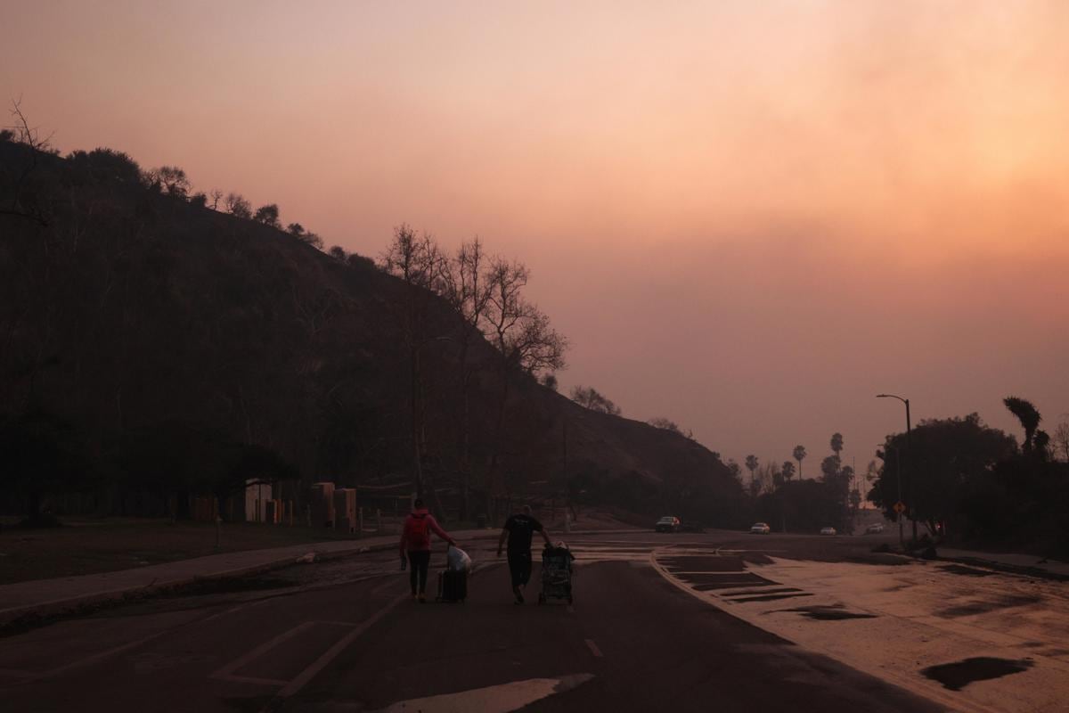 Personas evacuan con equipaje del incendio forestal en el barrio de Pacific Palisades de Los Ángeles (EFE)