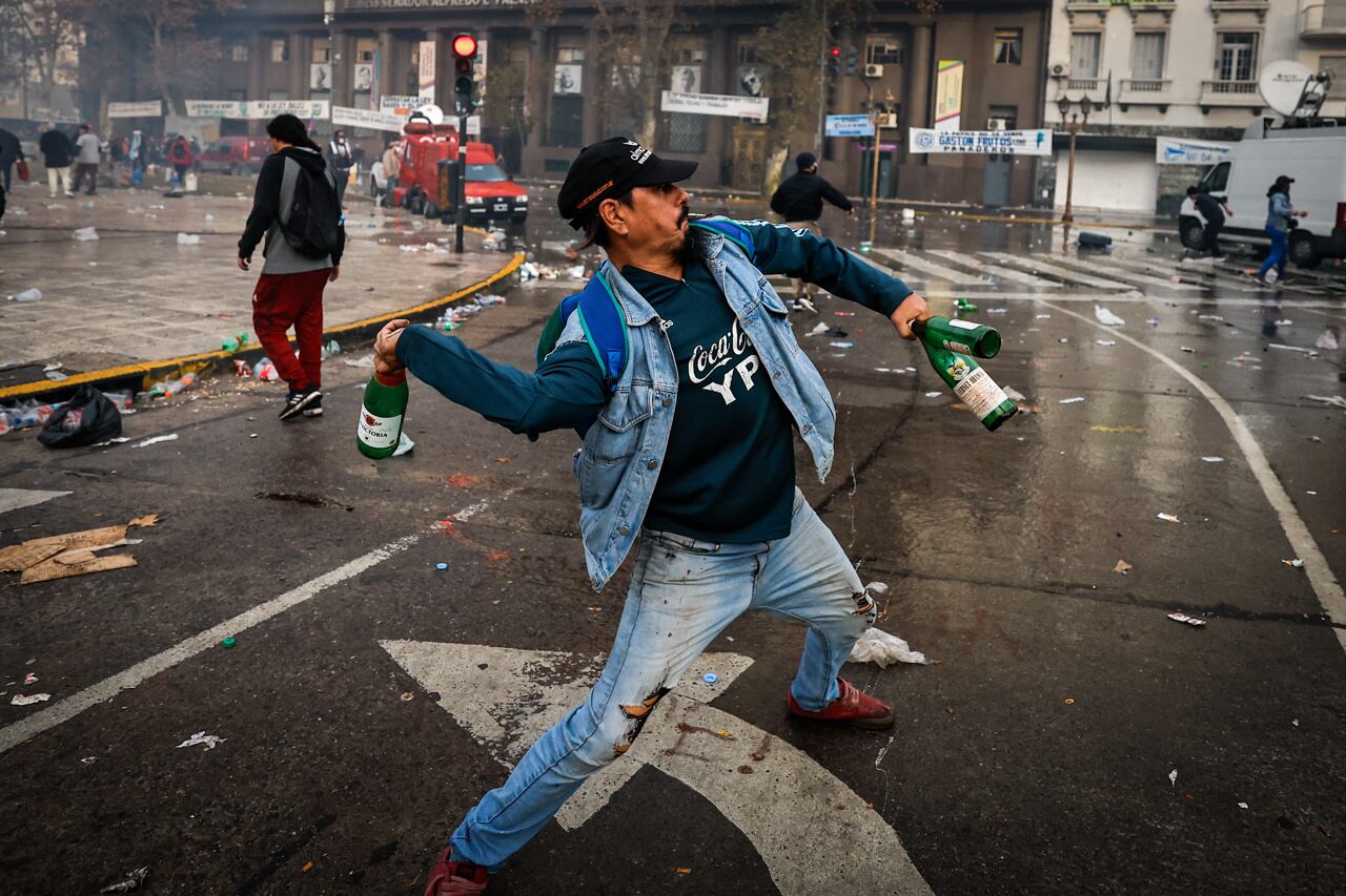 Un hombre lanza botellas de vidrio durante enfrentamientos entre la policía y personas que protestan a las afueras del senado. Foto: EFE/ Juan Ignacio Roncoroni