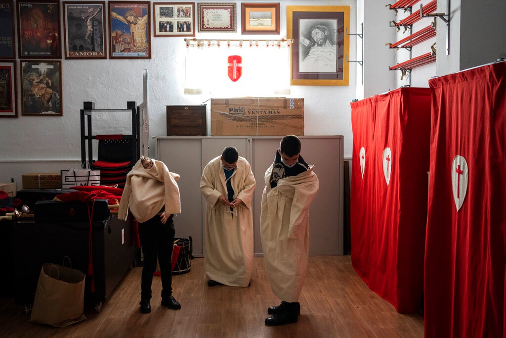 Penitentes de la Real Cofradía del Santísimo Cristo de las Injurias, también conocida como El Silencio, se visten antes de una procesión en Zamora, España, el 13 de abril de 2022. (AP Foto/Bernat Armangué)