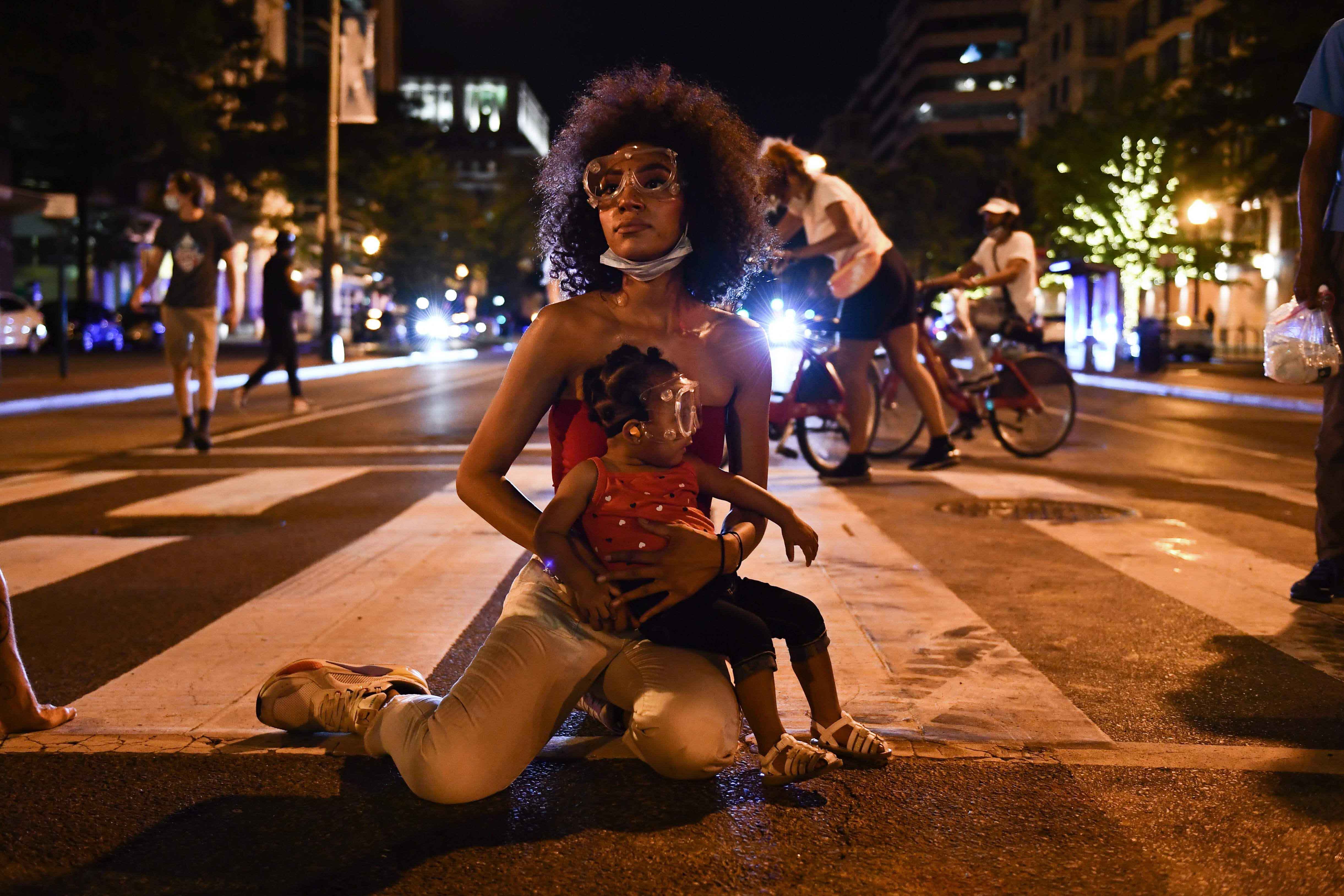 La manifestante Twana Buck y su hija Bonita se sientan en la calle cerca de la Casa Blanca mientras las protestas provocadas por la muerte de George Floyd mientras se encuentra bajo custodia policial continúan el 23 de junio de 2020 en Washington, DC.  / AFP / Brendan Smialowski