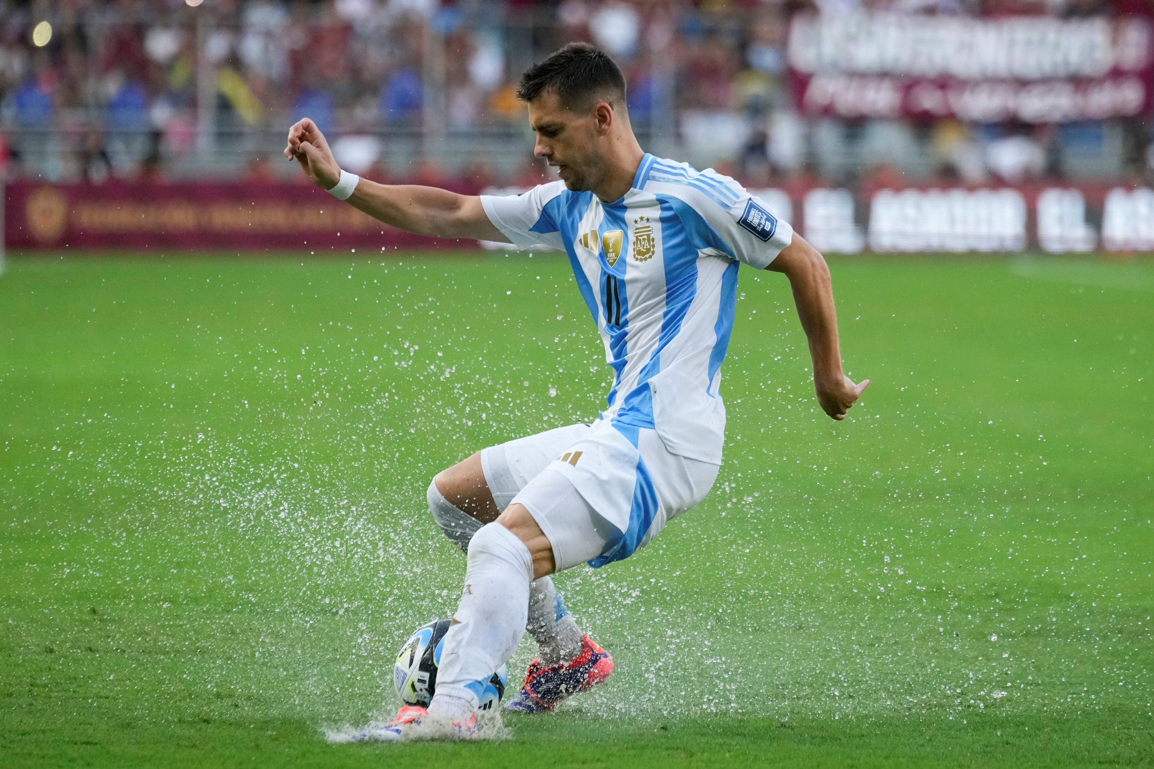 Lo Celso intenta dominar el balón en un campo de juego repleto de agua. / Foto: AP