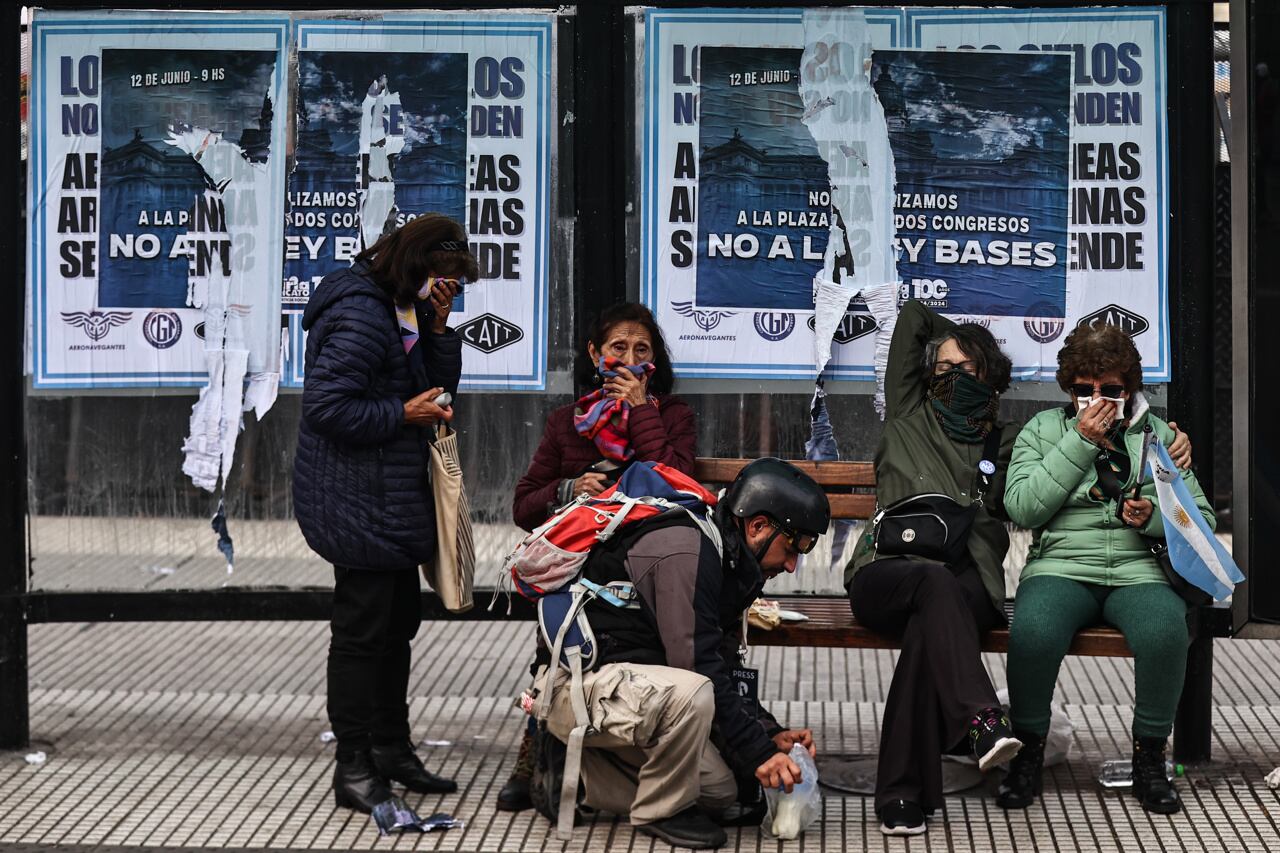 Personas se protegen de gases lacrimógenos durante enfrentamientos entre la policía y personas que protestan a las afueras del senado. Foto: EFE/ Juan Ignacio Roncoroni