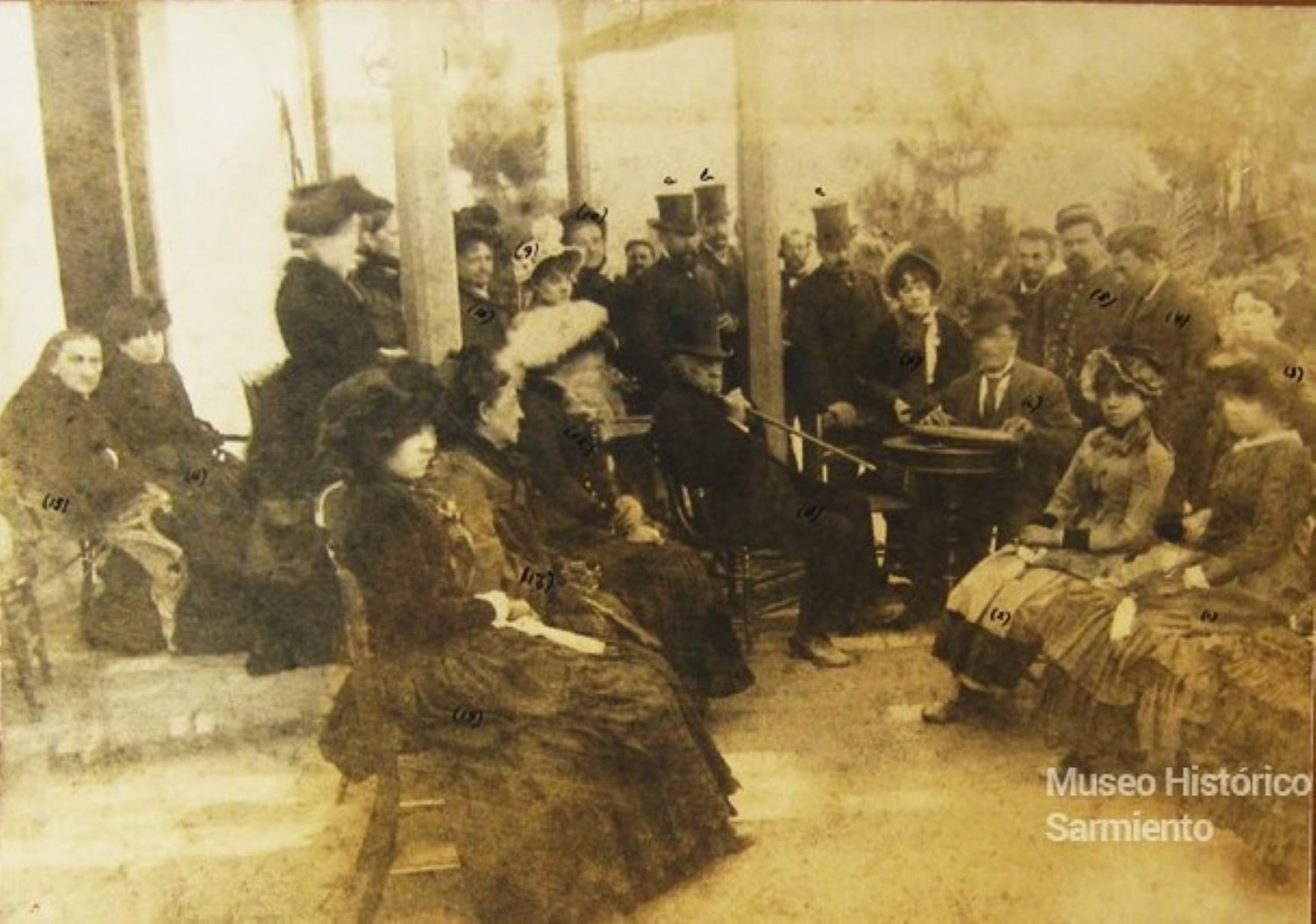 Domingo F. Sarmiento, se lo ve de piernas cruzadas en un cómodo sillón, en su mano derecha sostiene un bastón acústico, cuyo original se encuentra en el “Museo Histórico Sarmiento” de Buenos Aires; además estaban Ana Faustina Sarmiento de Belín ( hija ) que tenía 51 años entonces; Bienvenida Sarmiento, hermana mayor del prócer, tenía entonces 79 años;  Eugenia Belín Sarmiento, Emilia Belín Sarmiento, Luisa Belín Sarmiento, las tres son nietas de D.F.Sarmiento, hijas de Ana Faustina. También Agustín Klappenbach (13 años) , nieto de Procesa Sarmiento, hermana menor del prócer. Entre las personalidades destacamos El Gobernador de la provincia Gral. Rufino Ortega;  Francisco y Emilio Civit  anfitriones (Sarmiento estuvo alojado en su casa, actual “Museo del  Pasado Cuyano”) .  También estaba un músico de origen sueco que toca una cítara.