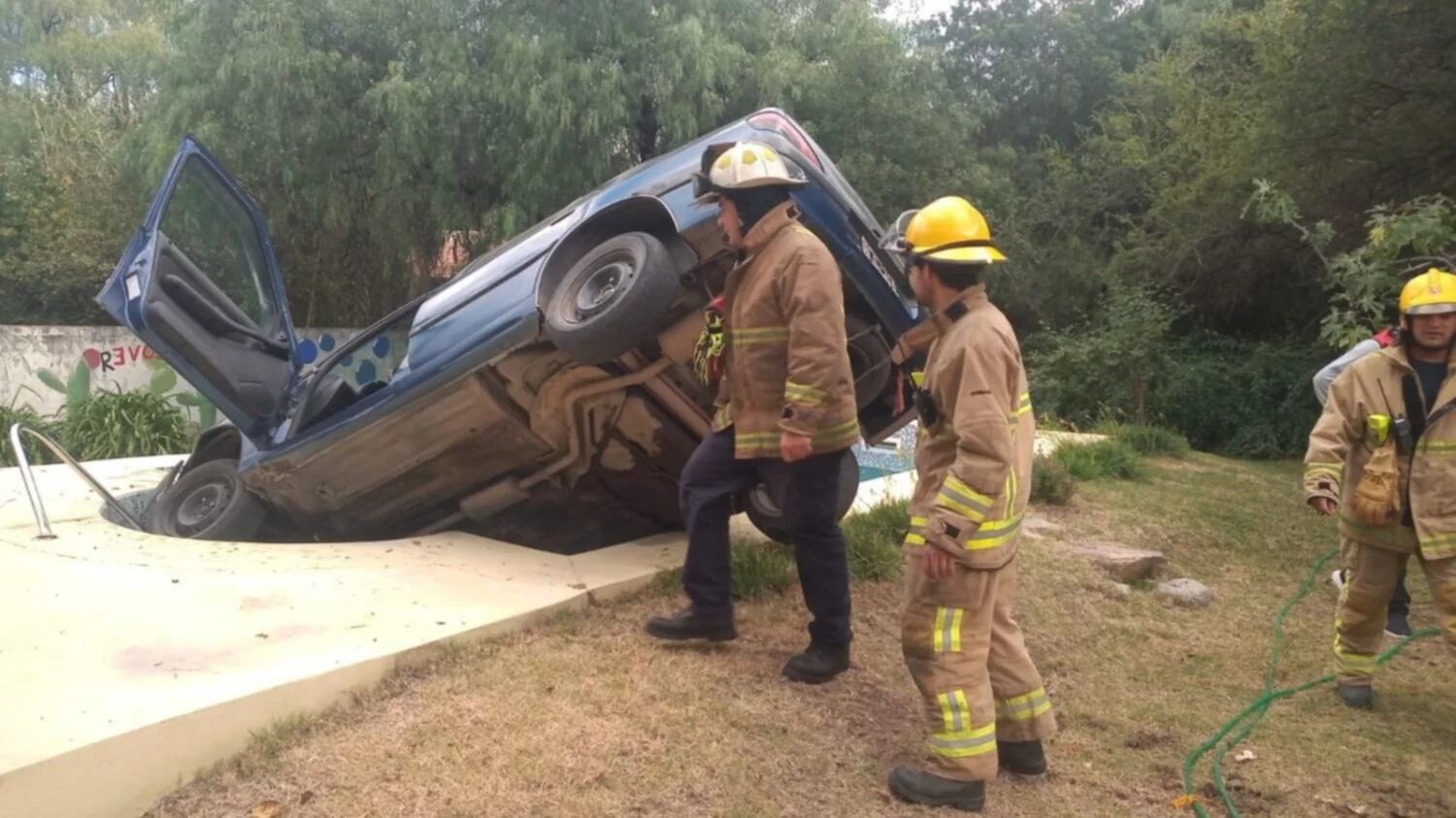 Bomberos voluntarios intentan sacar el auto de la pileta.