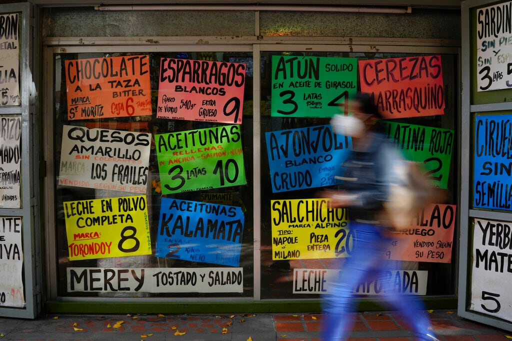 Una mujer pasa por delante de carteles que anuncian el precio de varios productos en dólares, en el exterior de una tienda de comestibles en Caracas, Venezuela