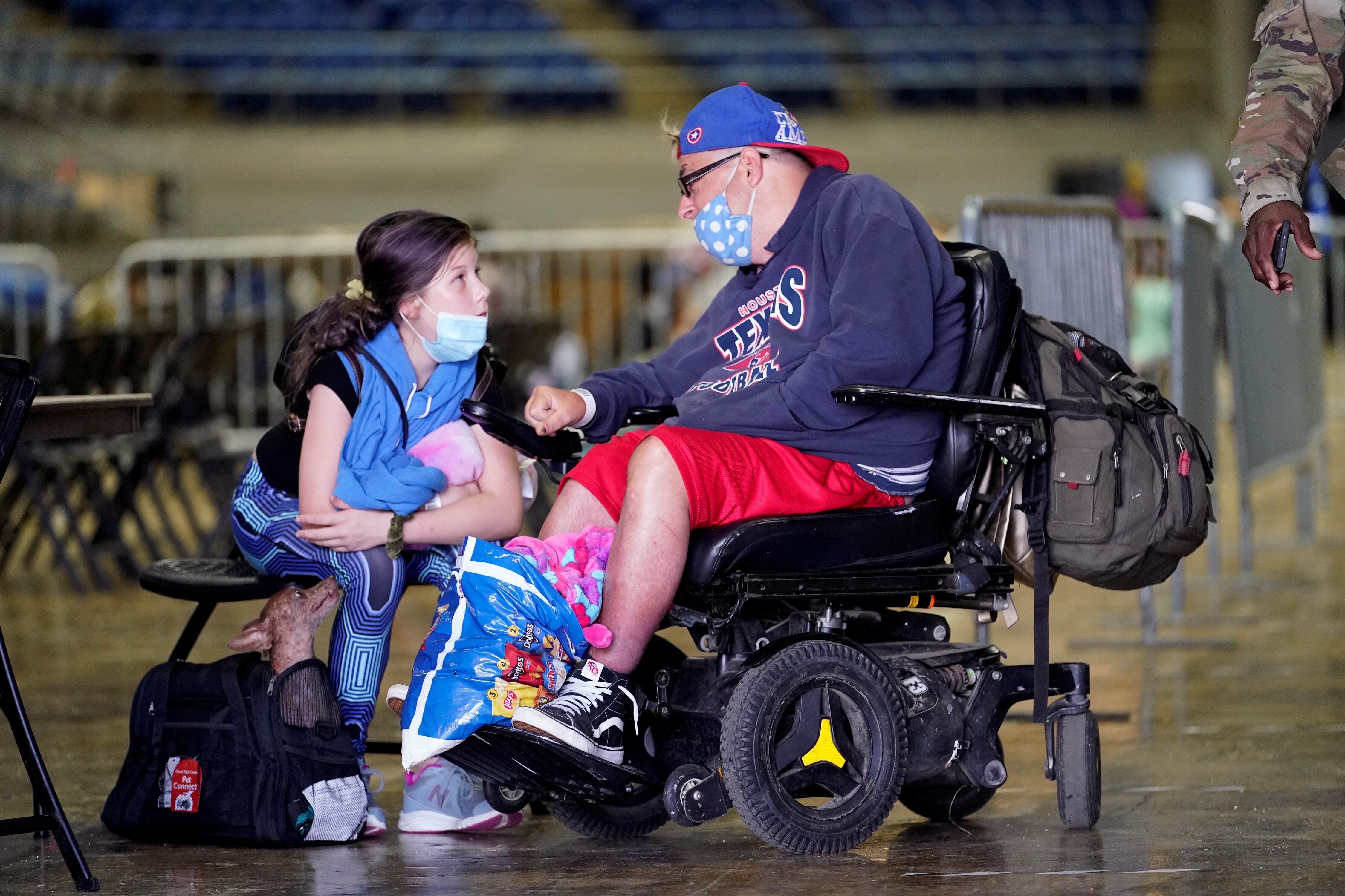 Hollie Duhon, de 13 años, habla con su tío, Eric Hogan, mientras esperan abordar un autobús para evacuar Lake Charles, Luisiana.