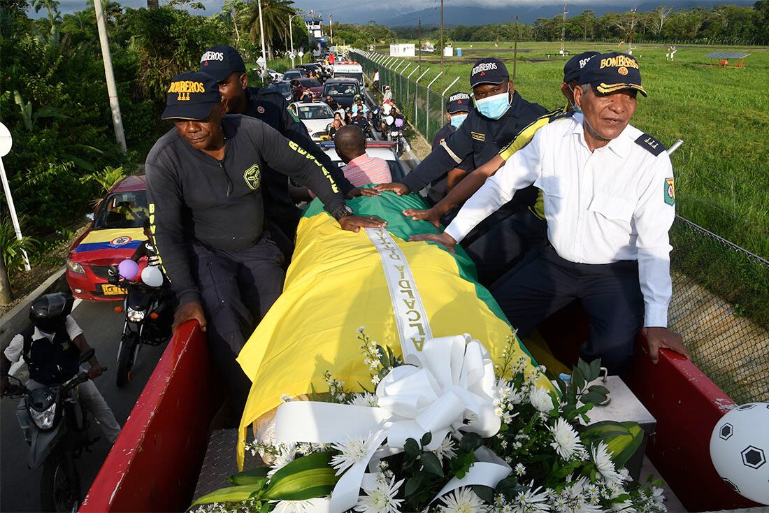 El féretro con el cuerpo del exfutbolista colombiano Freddy Rincón, cubierto con una bandera, es trasladado en un camión de bomberos al estadio de su ciudad natal, Buenaventura, Colombia, el 14 de abril de 2022. Rincón, excapitán de la selección nacional con la que disputó tres Mundiales, falleció tras un accidente de tráfico. Tenía 55 años. (AP Foto/Oswaldo Paez)