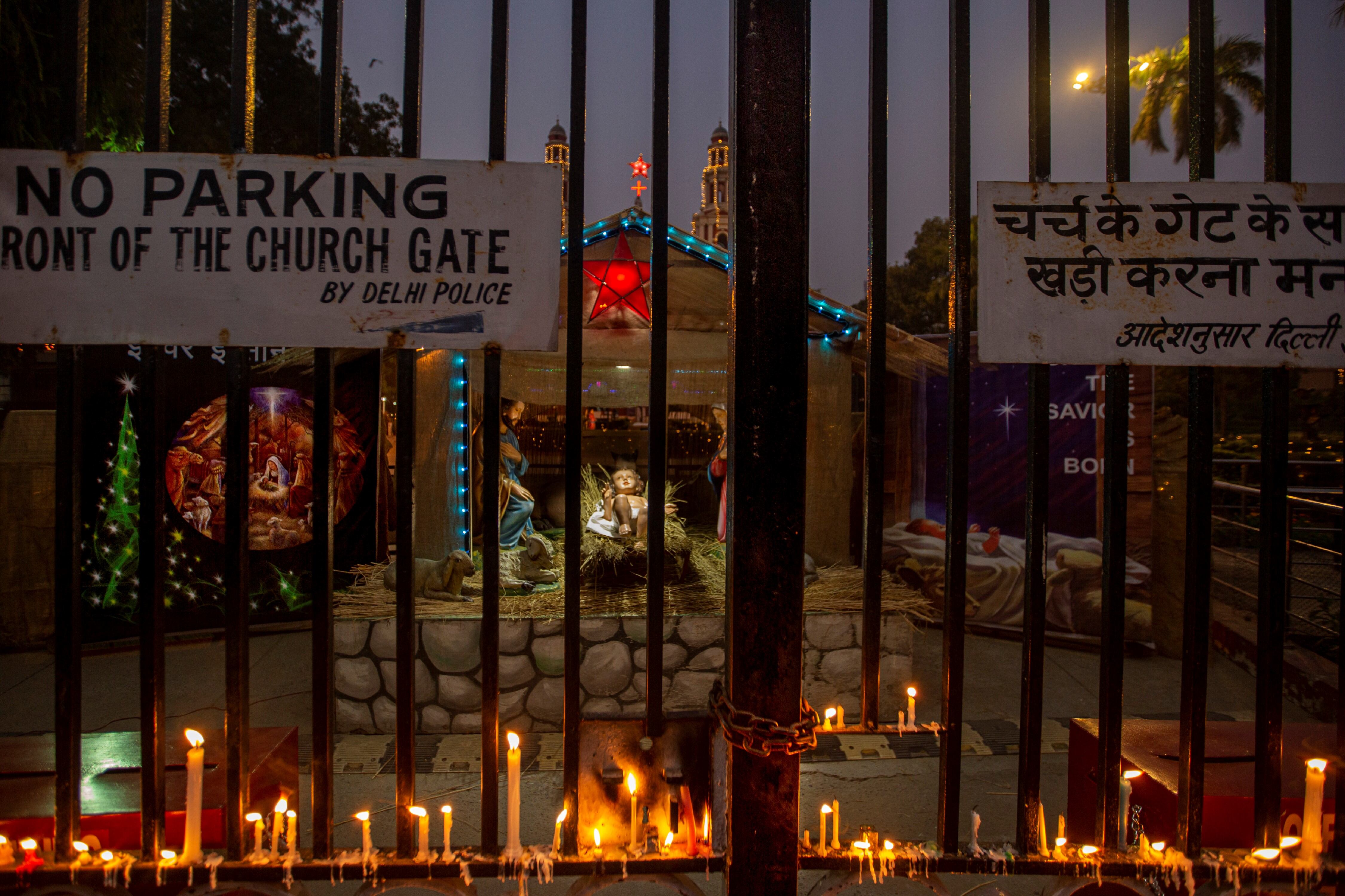 Las velas encendidas por los fieles se ven colocadas en la puerta de la Catedral del Hogar Sagrado, que está cerrada al público en general debido a las restricciones de COVID-19 en la víspera de Navidad en Nueva Delhi, India.