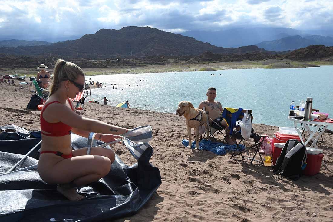 En la playa Bahía Príncipe del Dique Potrerillos, Julieta, armando una especie de carpa para disfrutar de la tarde en familia. Foto: José Gutierrez