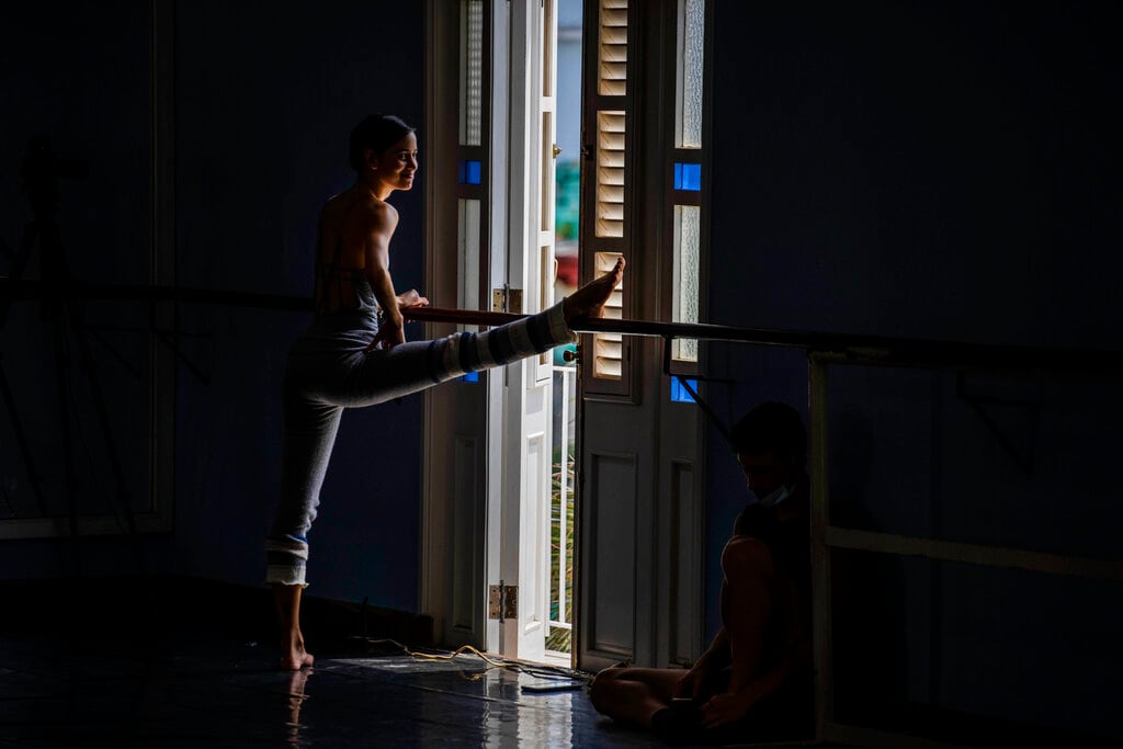 Una bailarina del Ballet Nacional de Cuba estira antes de un ensayo en la escuela del ballet en La Habana, el 5 de abril de 2022. El Ballet Nacional de Cuba empezó a ensayar para regresar a los escenarios tras más de un año luego de las restricciones por la pandemia del coronavirus. (AP Foto/Ramón Espinosa)