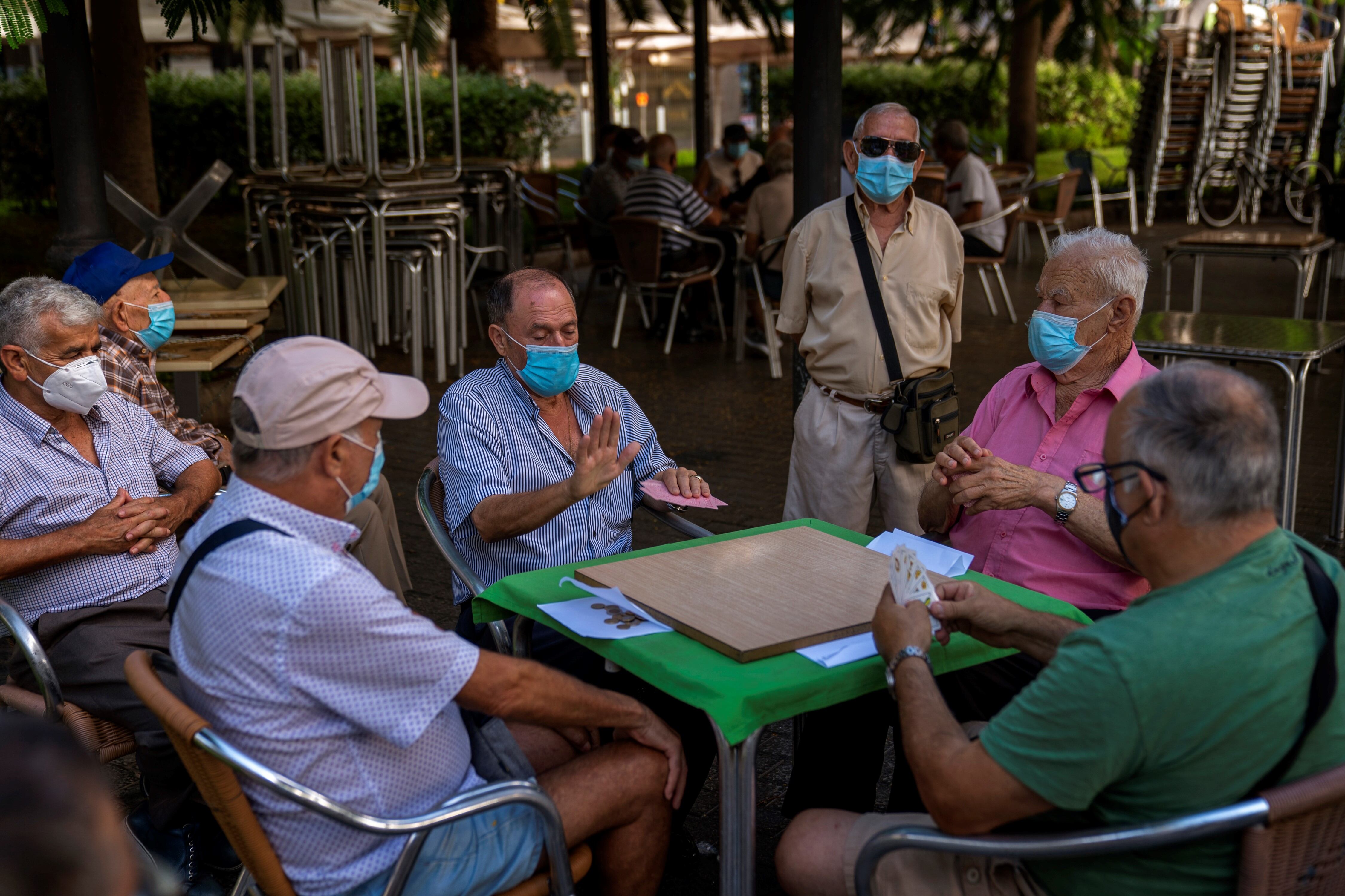 Hombres jubilados con mascarillas contra la propagación del nuevo coronavirus, juegan a las cartas en un parque en la isla de Gran Canaria, España. AP