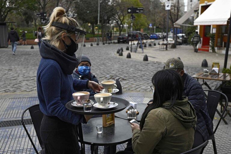 Una moza con máscara atiende un café en Buenos Aires. Archivo. 