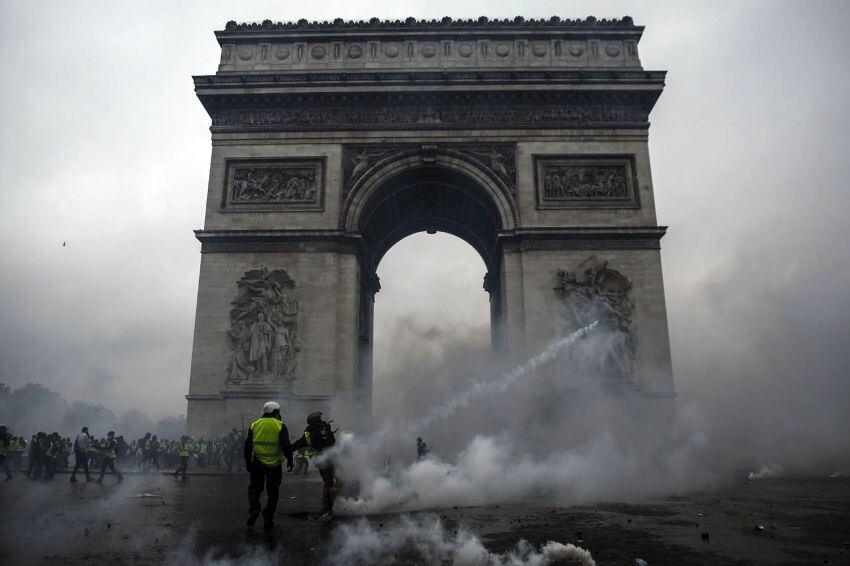 
Foto: AFP | Manifestantes se enfrentan a la policía antidisturbios en el Arco de Triunfo durante una protesta de los chalecos amarillos.
   